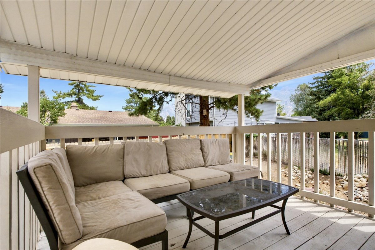 Covered outdoor deck featuring white wood-finish flooring, a full railing, and a slatted ceiling