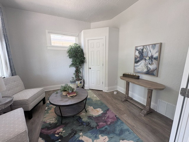 Light-filled interior space featuring wood-finish flooring, a white paneled door, and a horizontal window