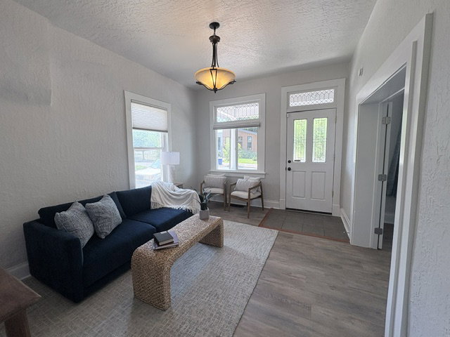 Entryway featuring a decorative transom window above a panel door, wood-finish flooring, and a classic pendant light fixture