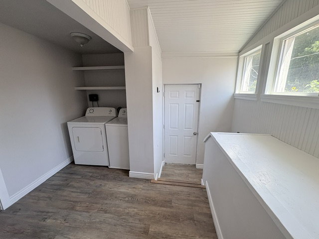 Dedicated laundry area with built-in shelving, wood-finish flooring, and bright white beadboard paneling