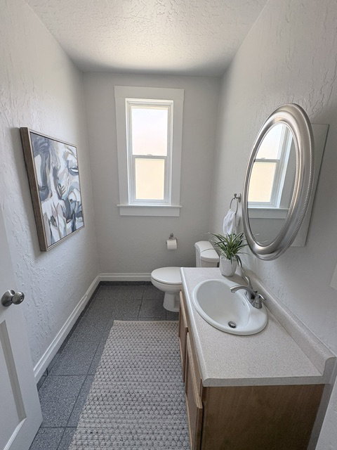 Compact bathroom featuring a single window, tiled flooring, and a wood-finish vanity with an integrated sink