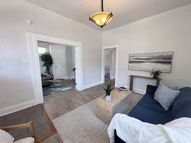 Spacious living area featuring light neutral wall tones, wood-finish flooring, and white trim