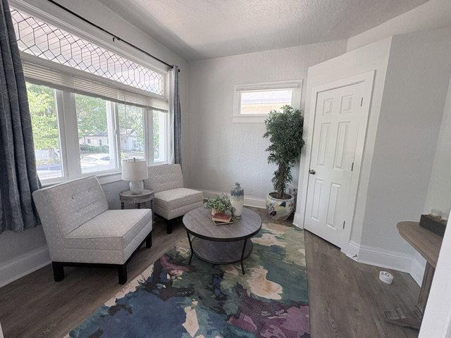 Bright room featuring large windows with decorative transom, wood-finish flooring, and a paneled door