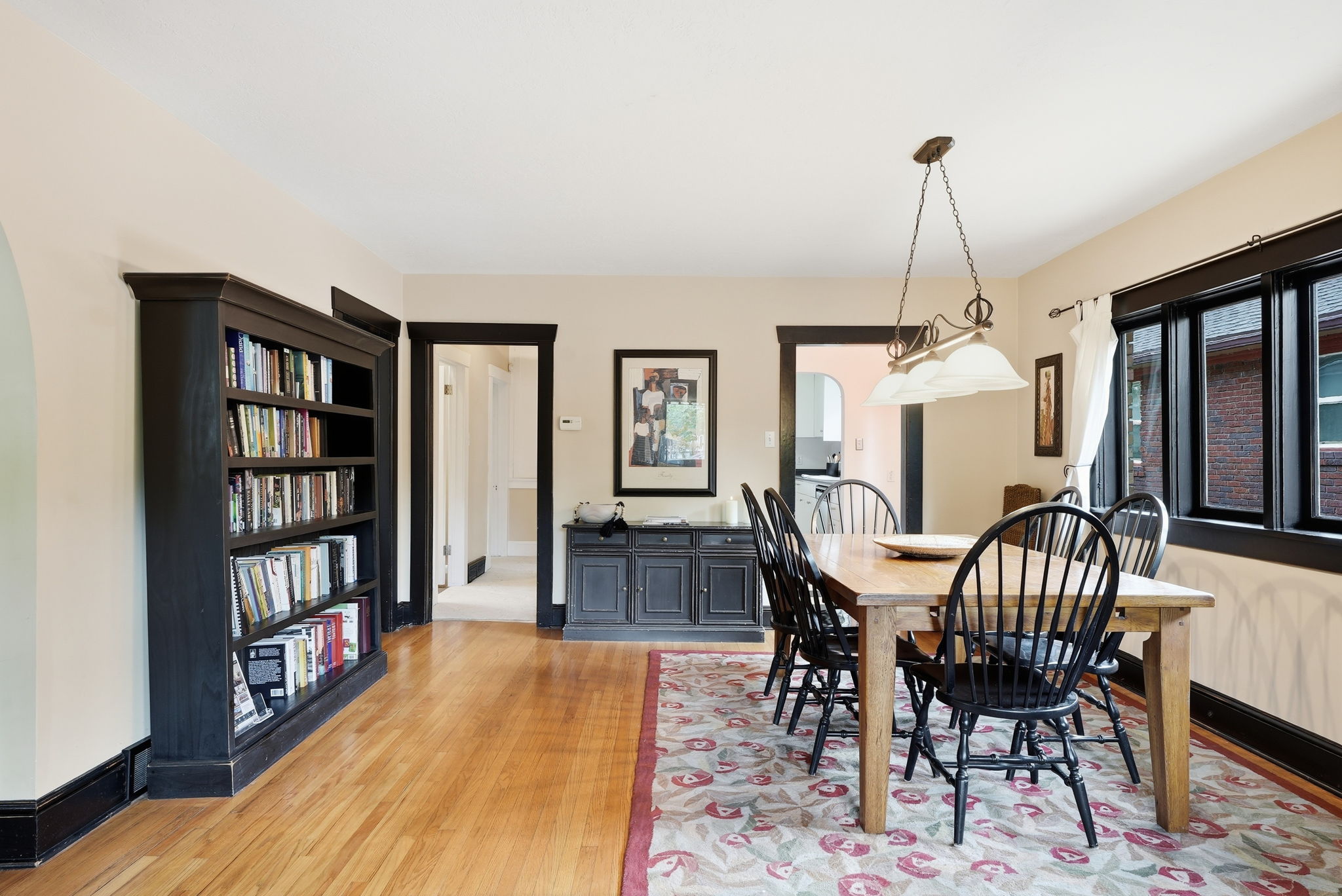 Dining area featuring hardwood flooring, dark trim work, built-in shelving, and a multi-pane window