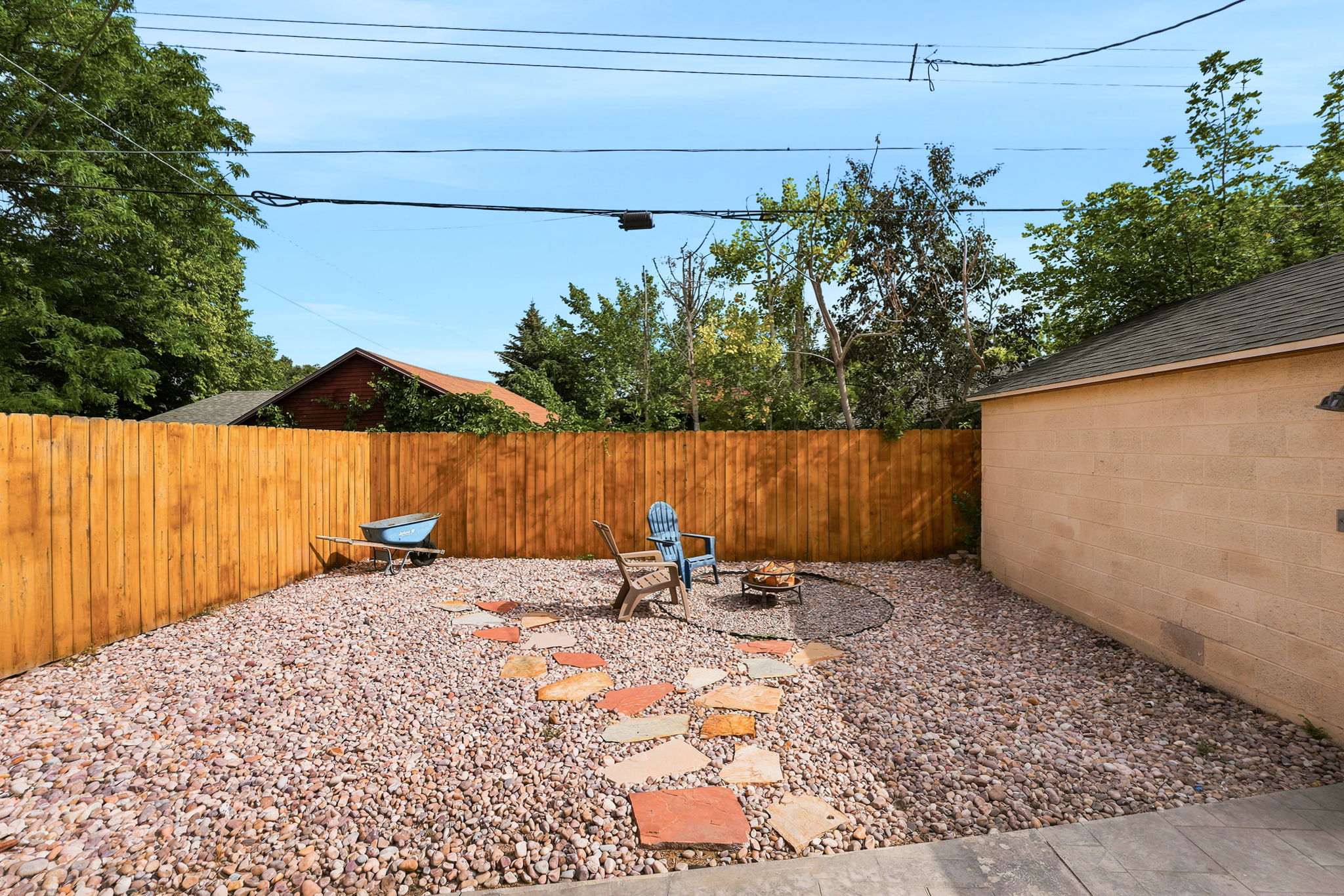 Gravel yard featuring a wood privacy fence, stone paver pathway, and an established fire pit area