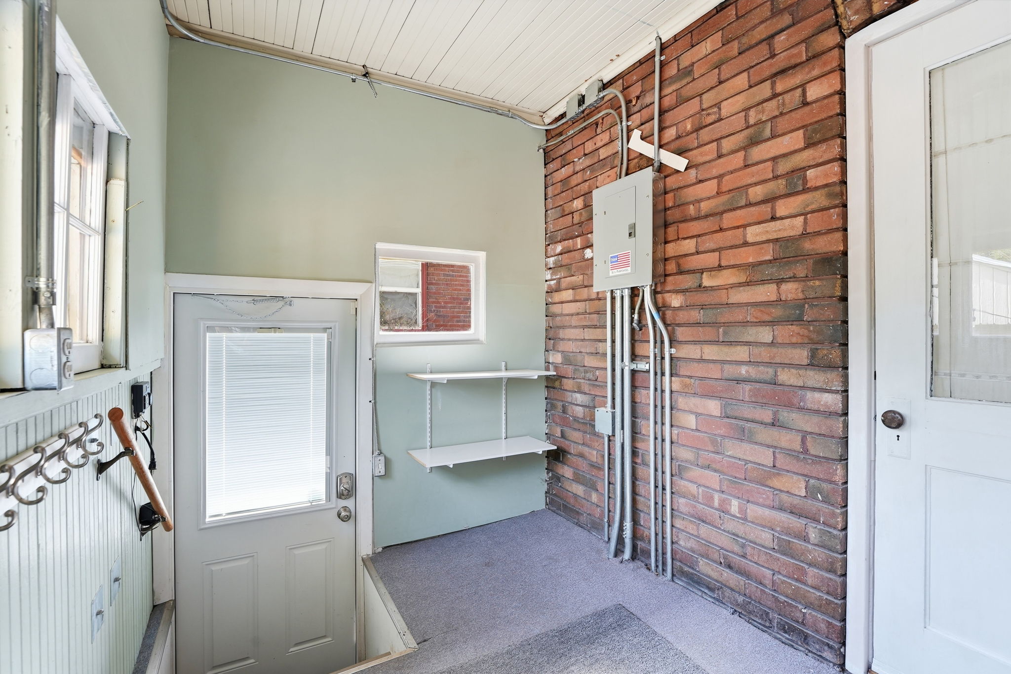 Foyer featuring exposed brick wall, painted tongue-and-groove ceiling, and a full-light entry door