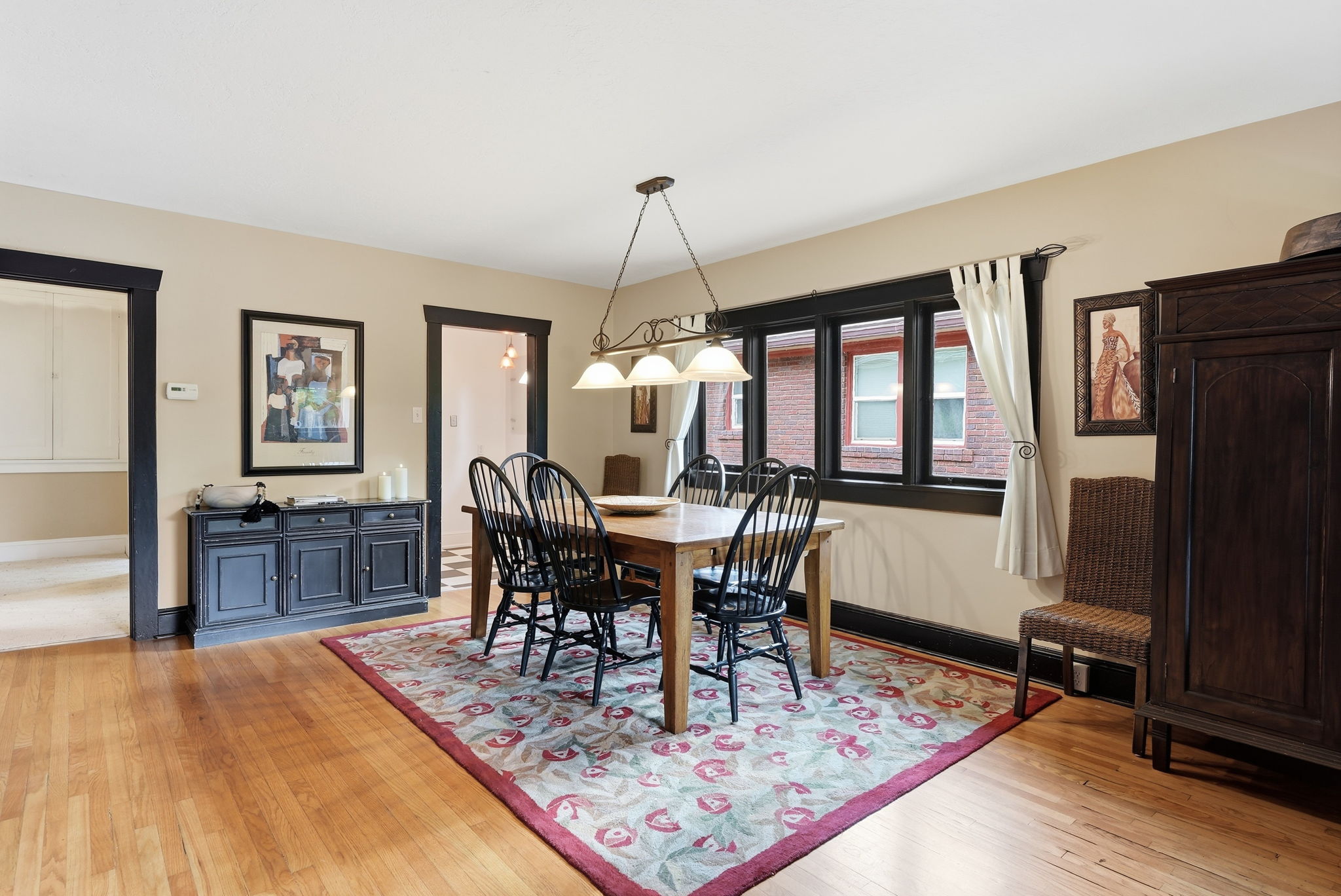 Dining area with wood-finish flooring, featuring a multi-light chandelier and dark trim accents