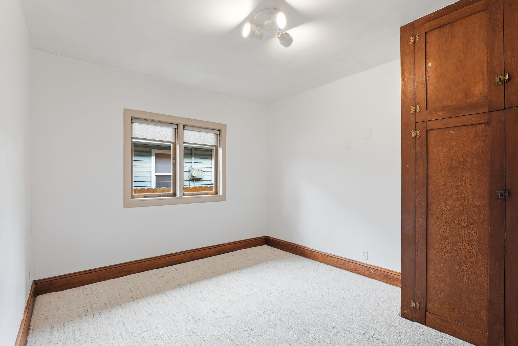 Room featuring a single window, white walls, and wood trim