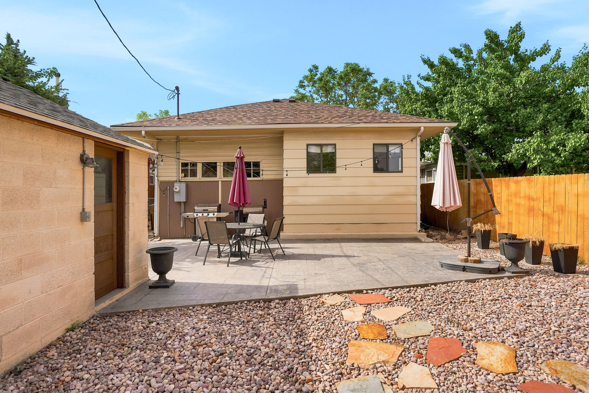 Spacious backyard featuring a large concrete patio, a gravel ground cover, and a multi-toned flagstone path