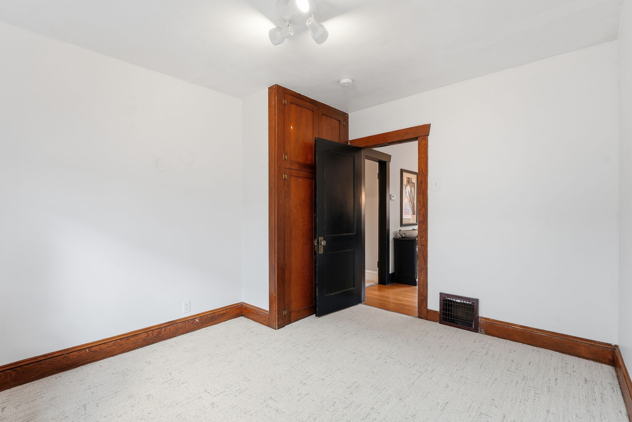 Room featuring white walls, textured carpeting, and wood baseboards