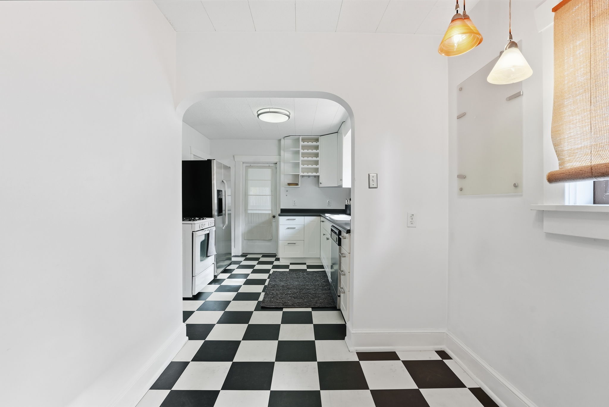 Archway entrance to a kitchen featuring checkerboard flooring