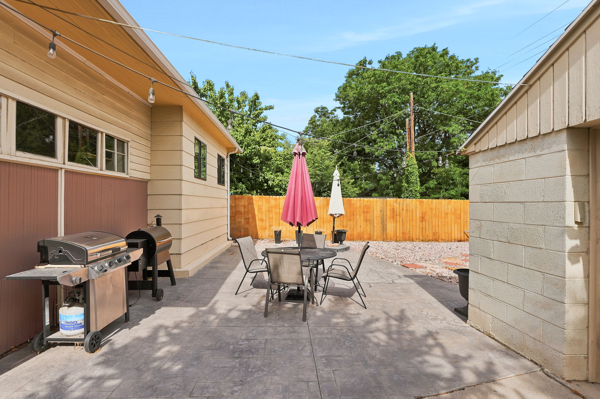 Stamped concrete patio with string lighting and a wood privacy fence