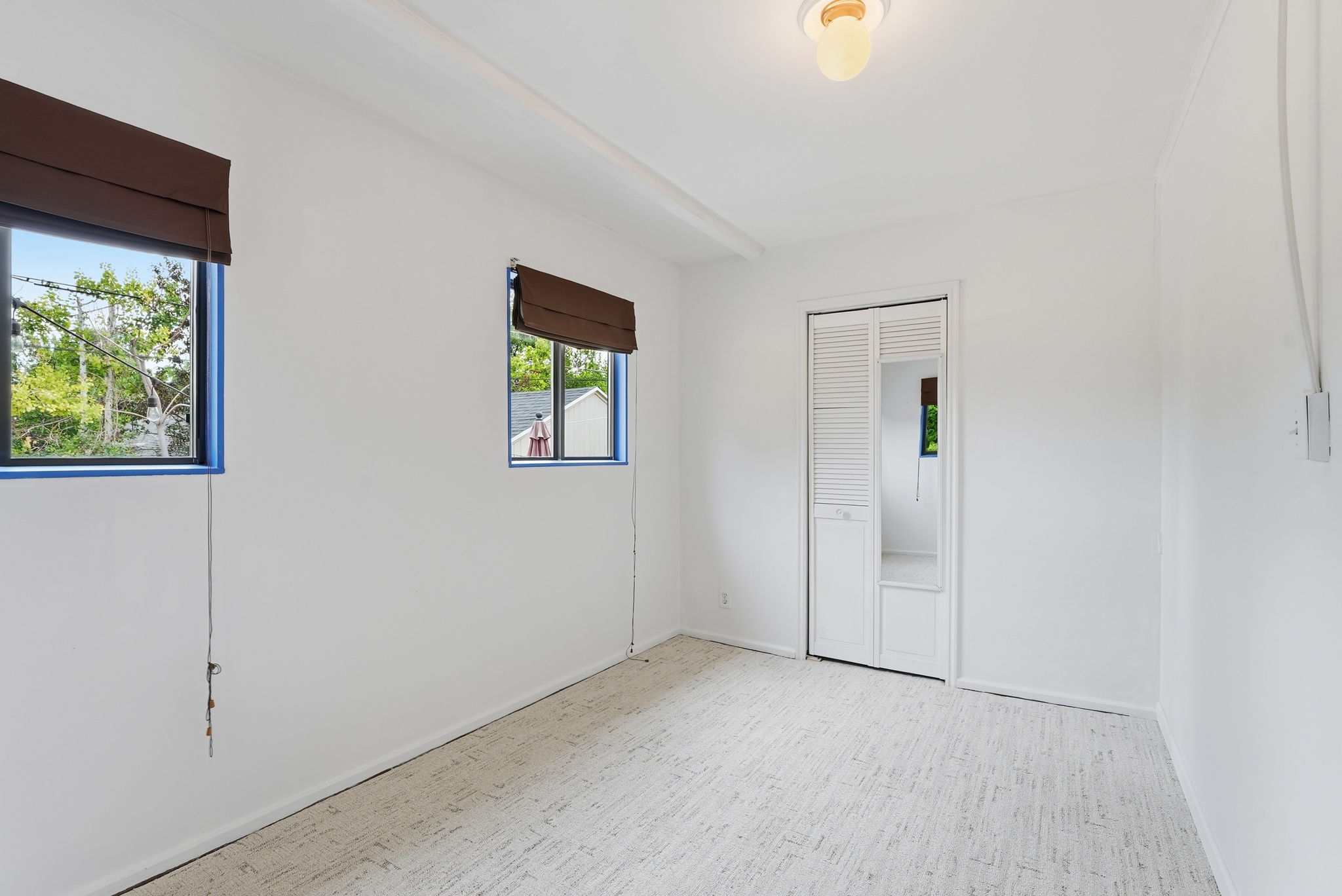 Bright interior space featuring two large windows, white walls, and light-toned flooring