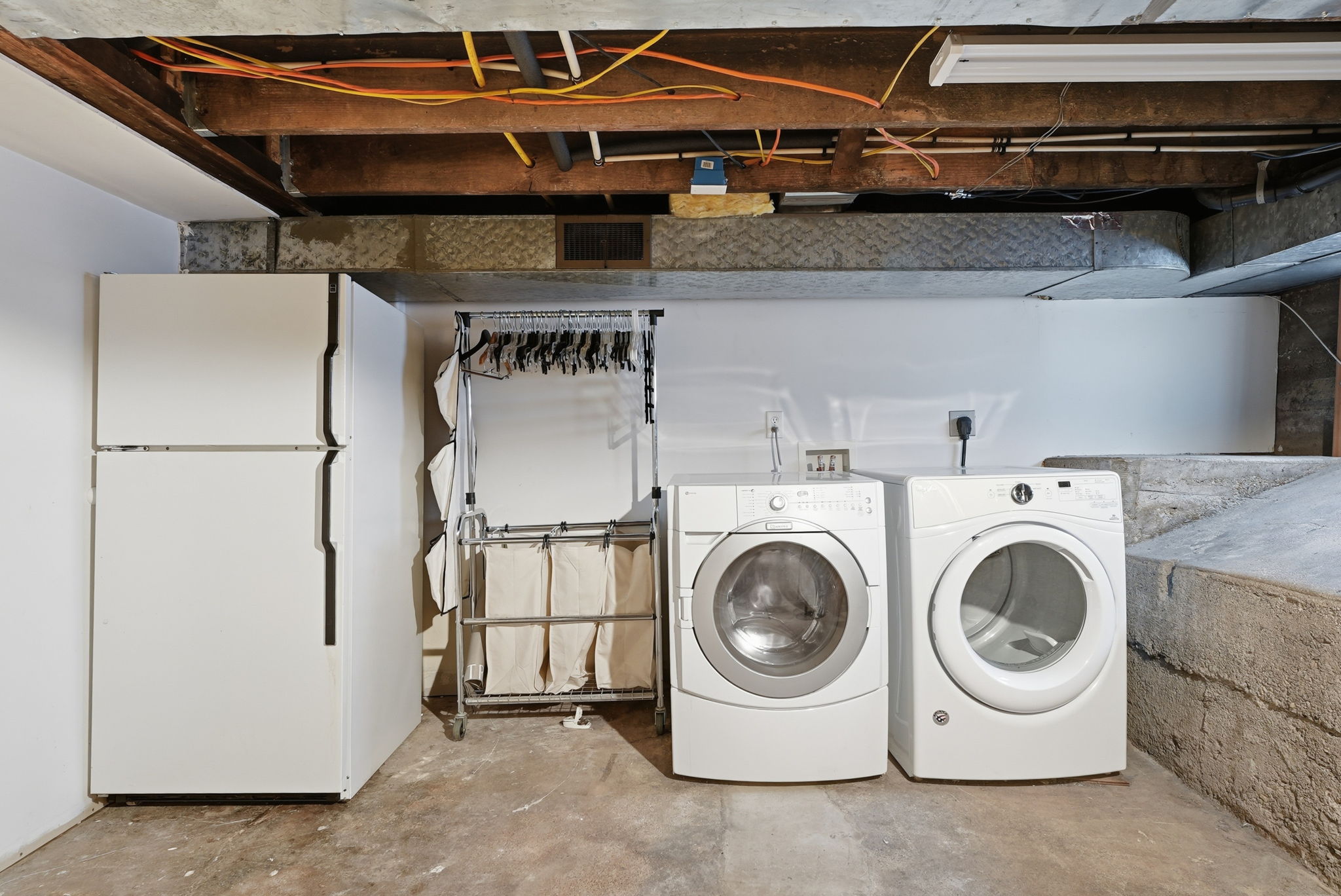 Utility space featuring a stacked washer and dryer, along with a white refrigerator