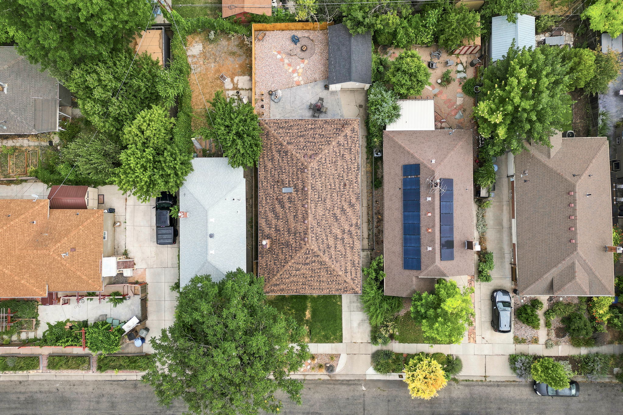 Residential property with a brown shingle roof, extensive backyard with mature trees, and a concrete driveway