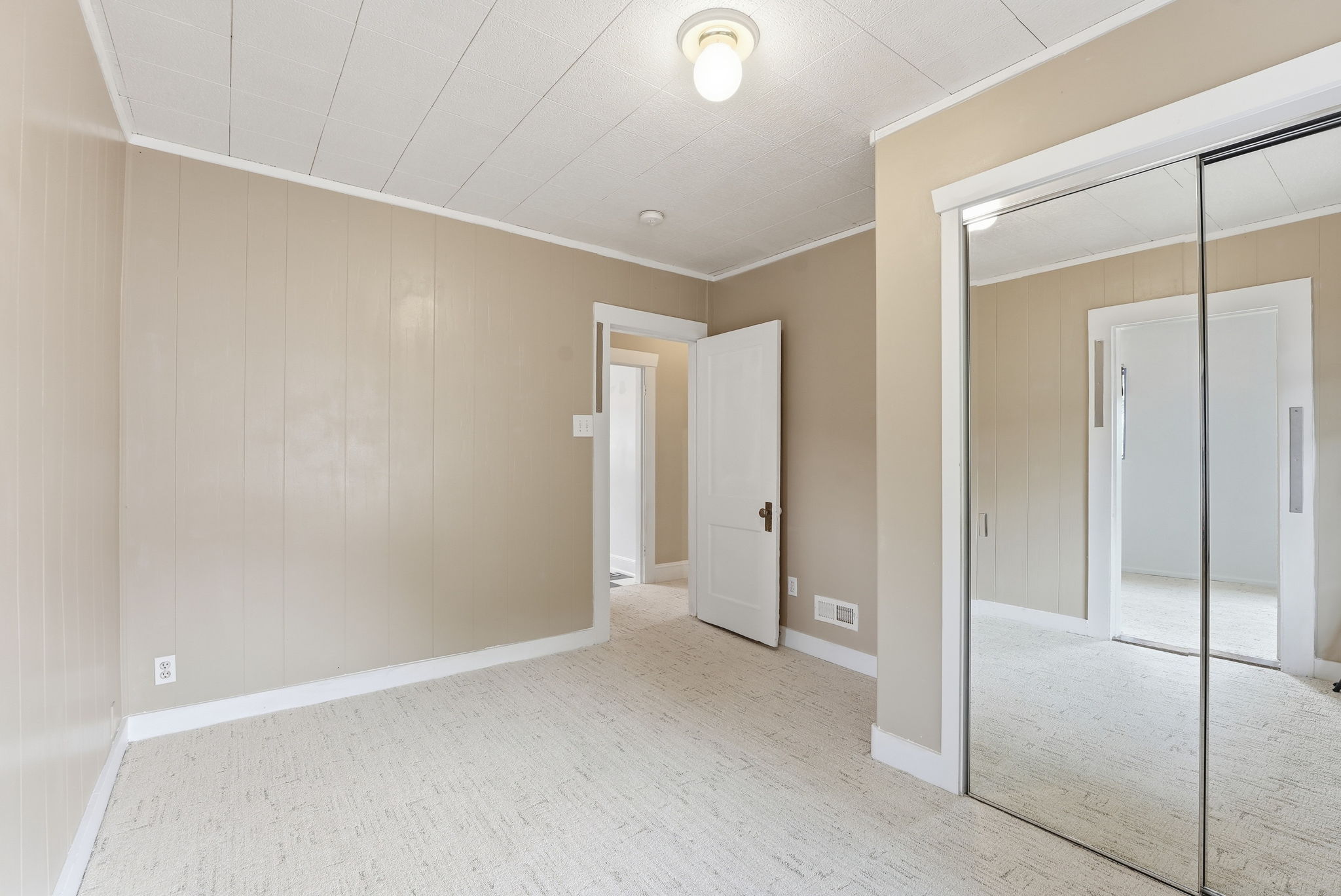 Neutral-toned bedroom featuring paneled walls, a textured ceiling, and patterned carpeting