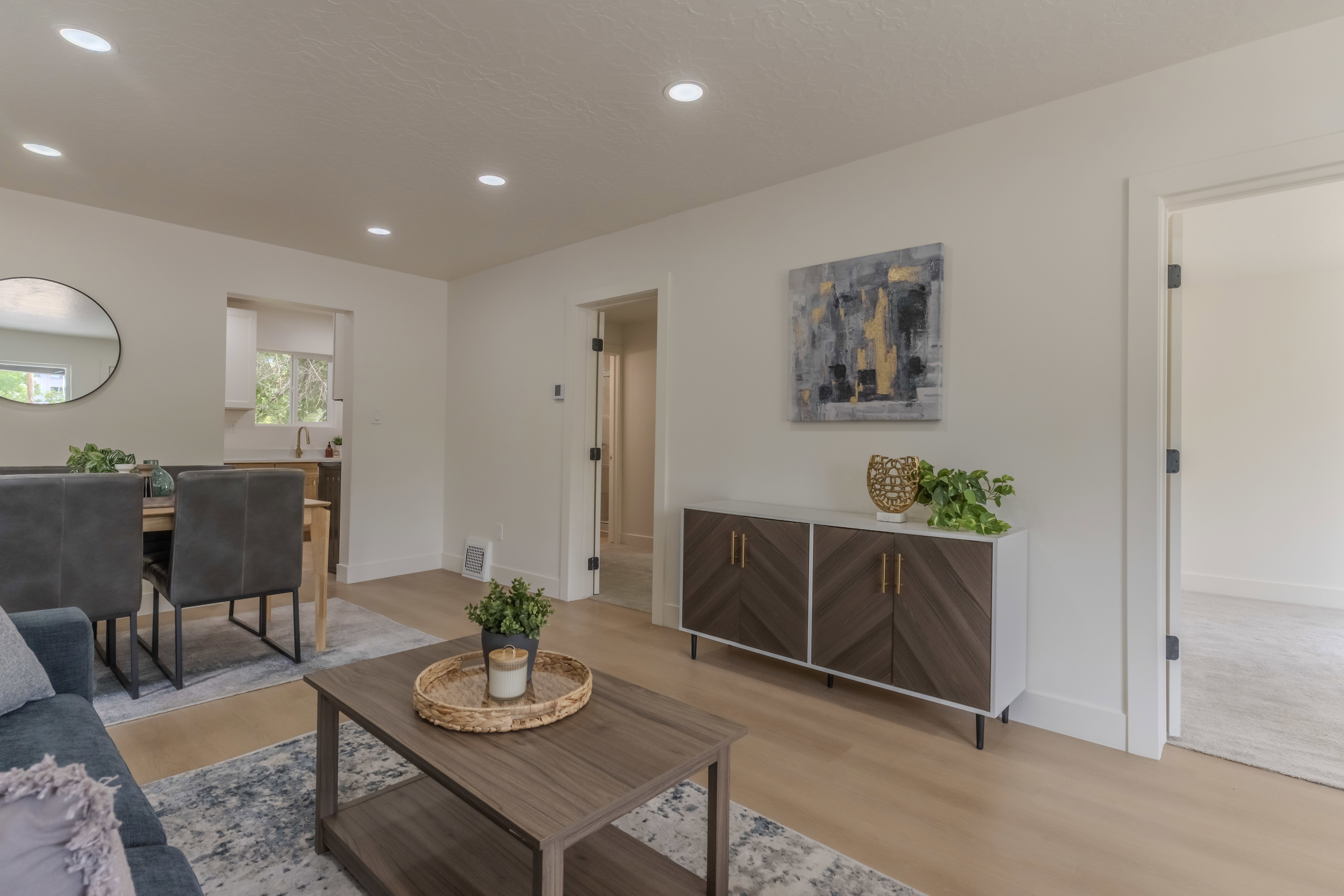 Open-concept living area featuring light wood-finish flooring, recessed lighting, and crisp white walls