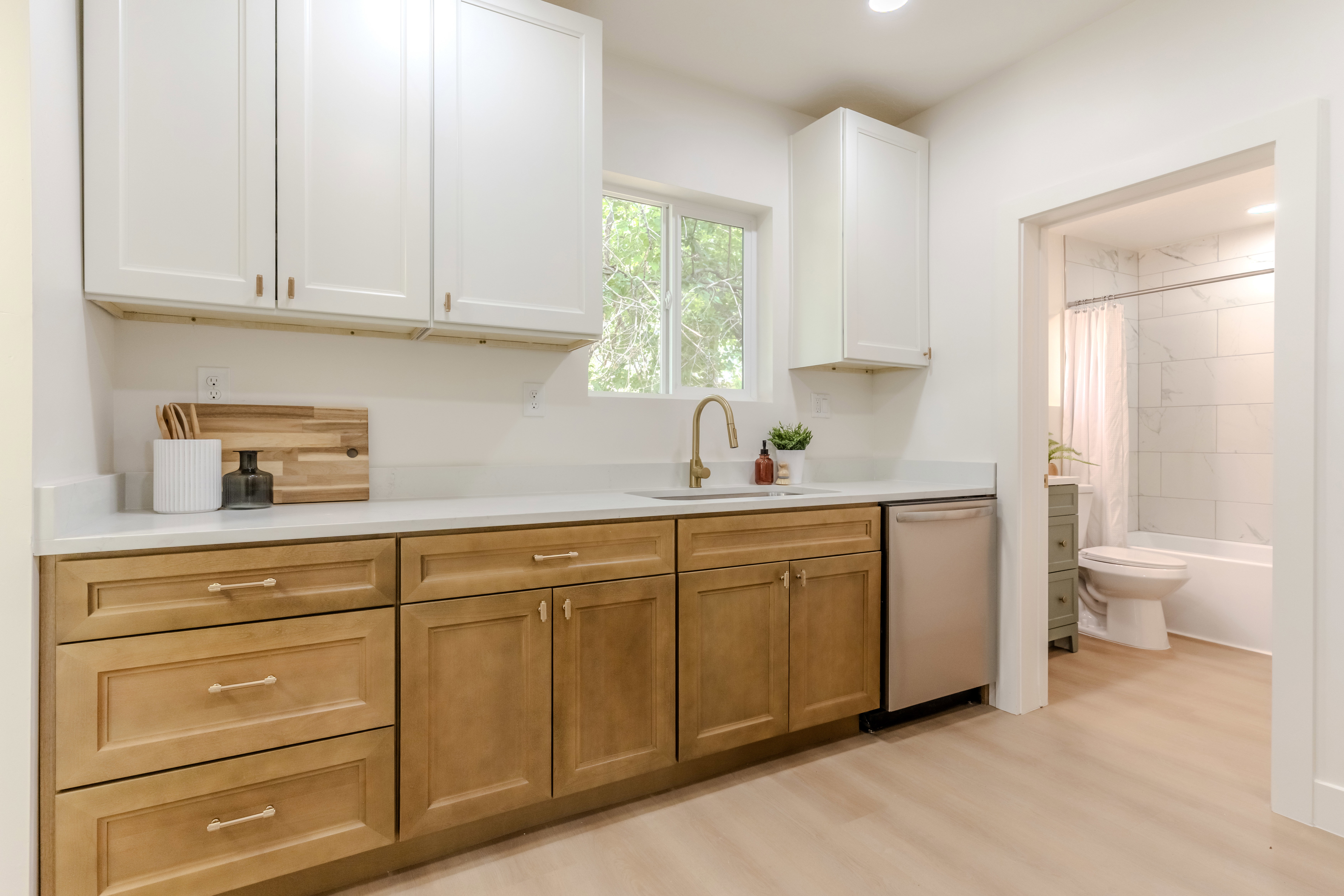 Kitchenette featuring two-tone cabinetry, a stainless steel dishwasher, and a window above the sink