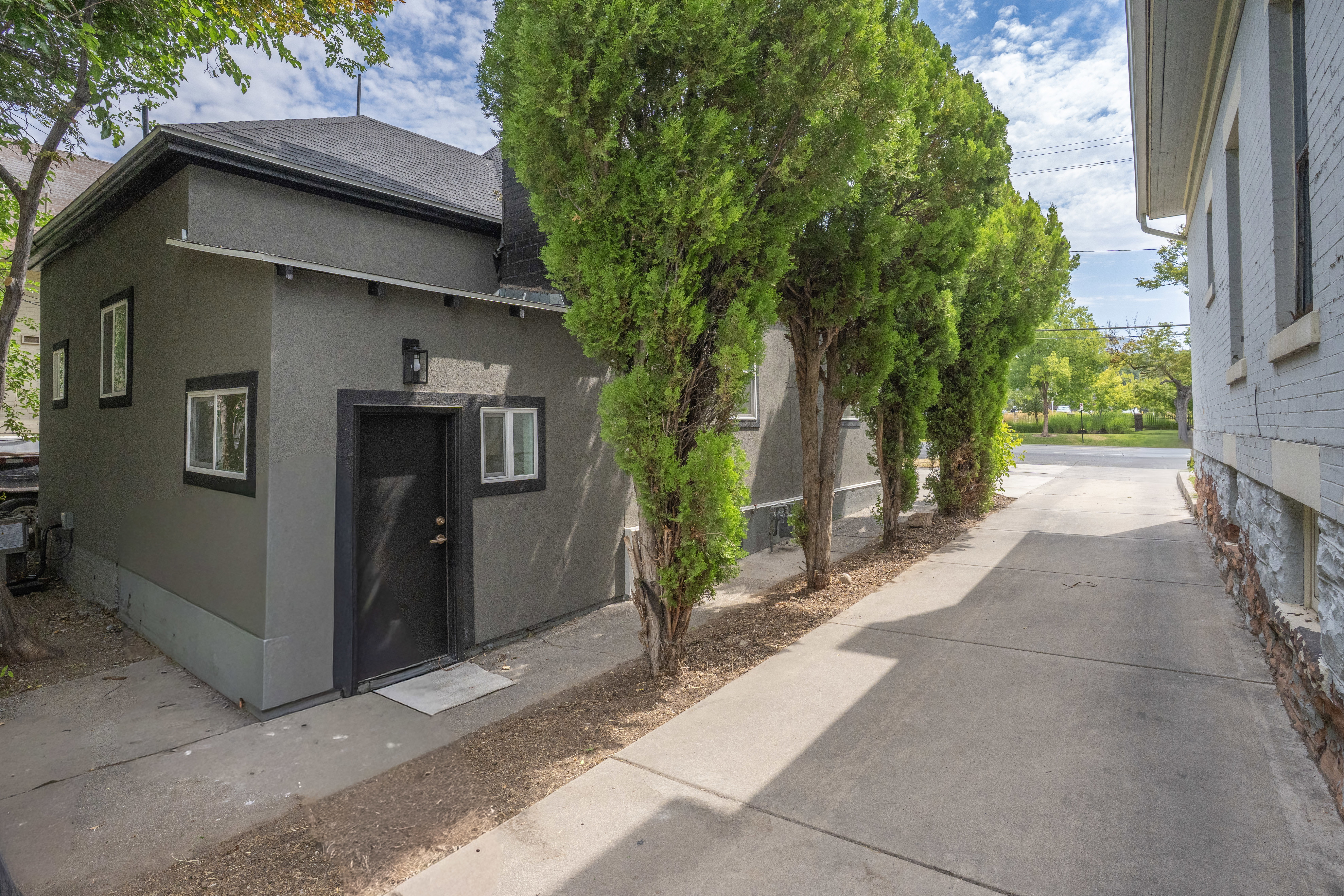 Gray stucco exterior with black trim and a dark asphalt shingle roof
