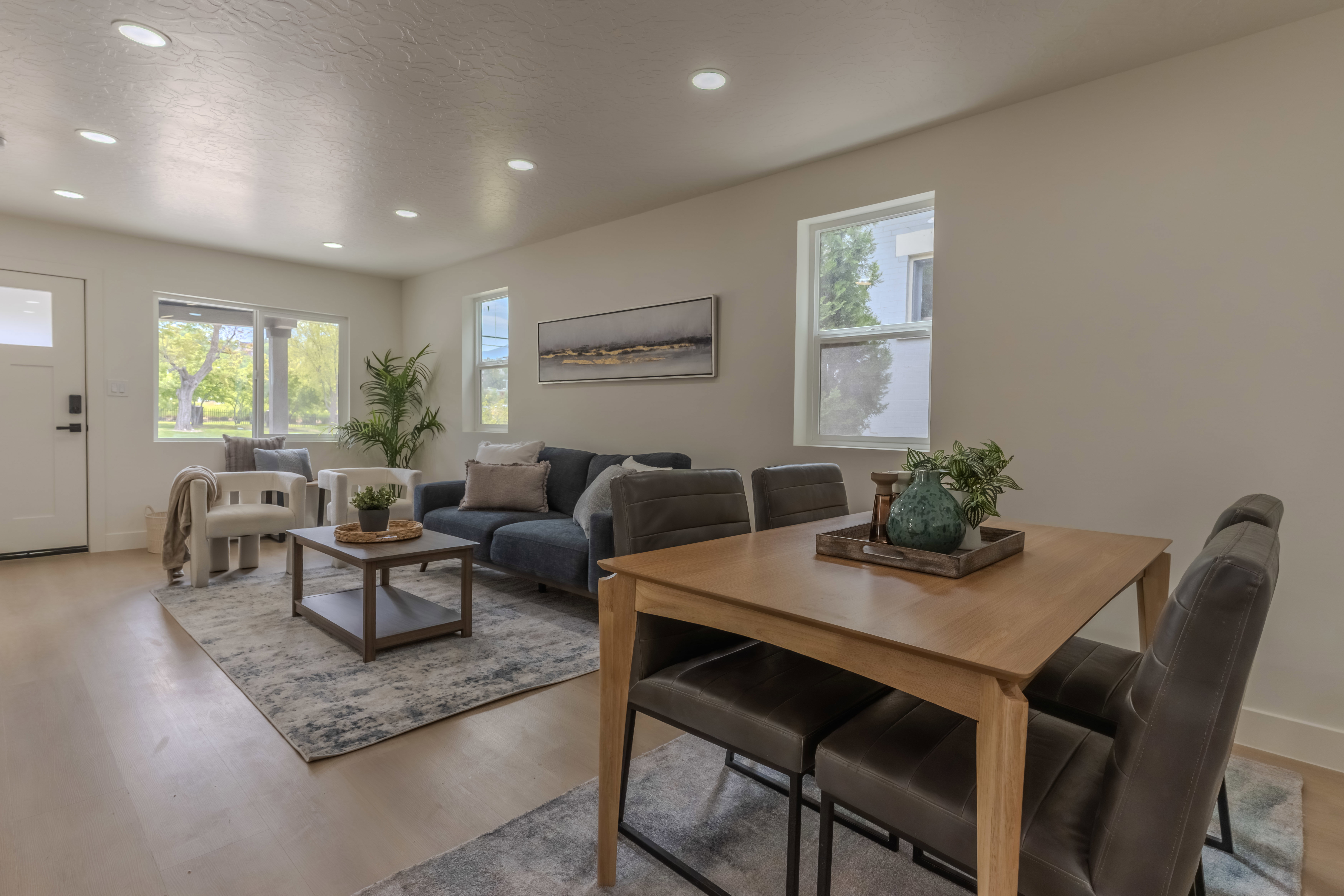 Open-concept living and dining area featuring light wood-finish flooring, recessed lighting, and multiple windows