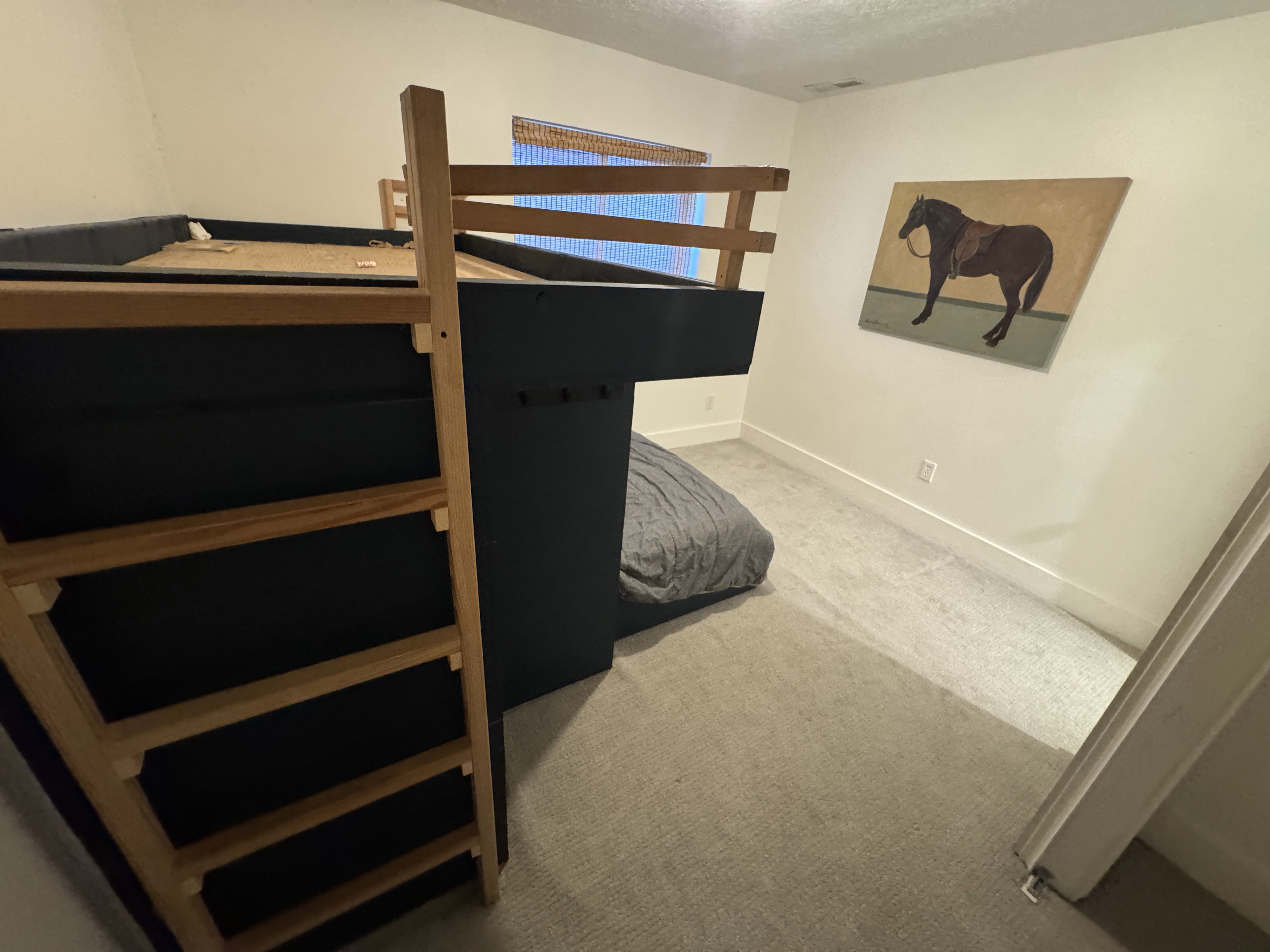 Built-in loft bed with light-toned wood frame and ladder