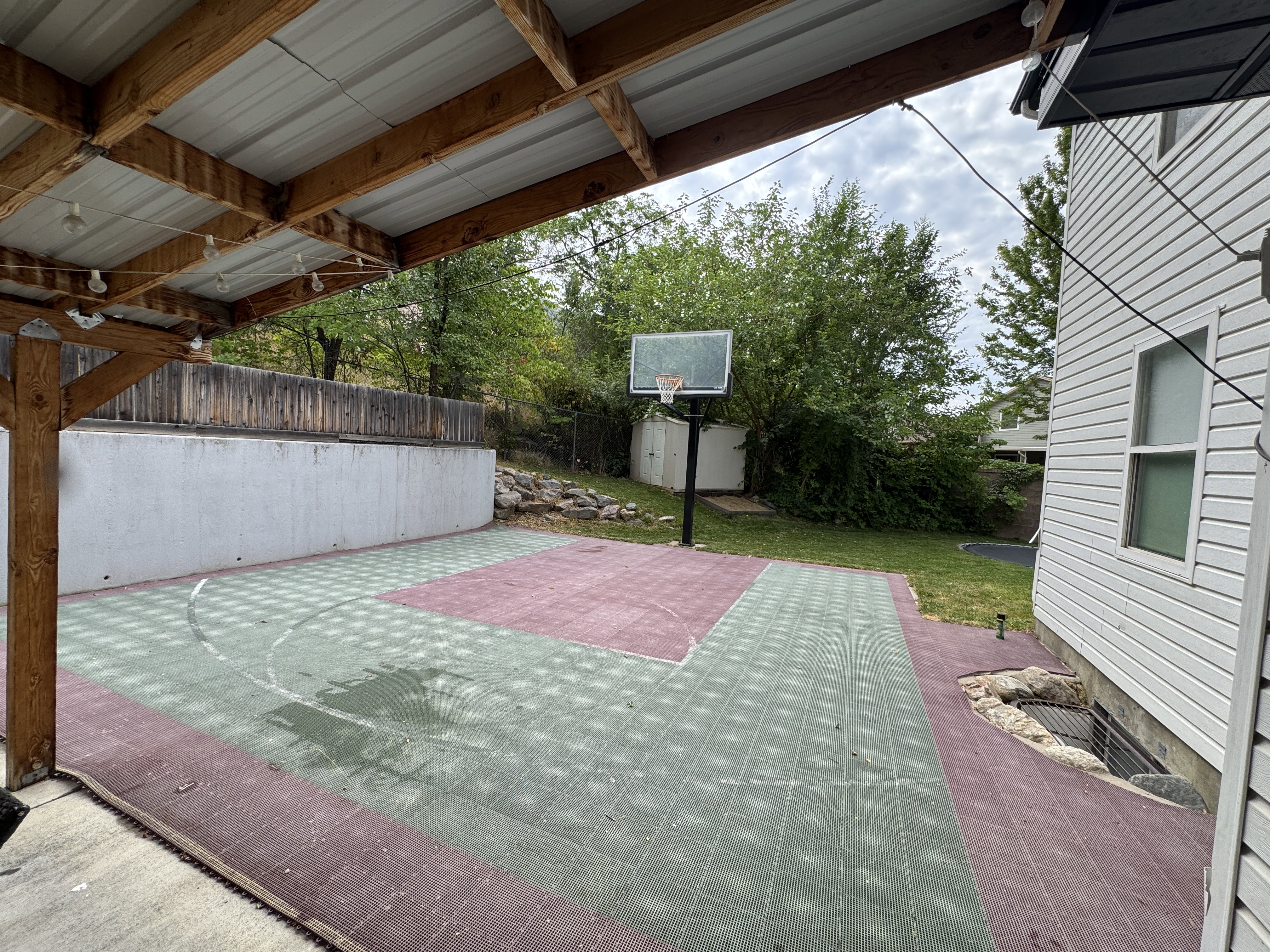 Outdoor sport court featuring a basketball hoop and a green and red checkered surface