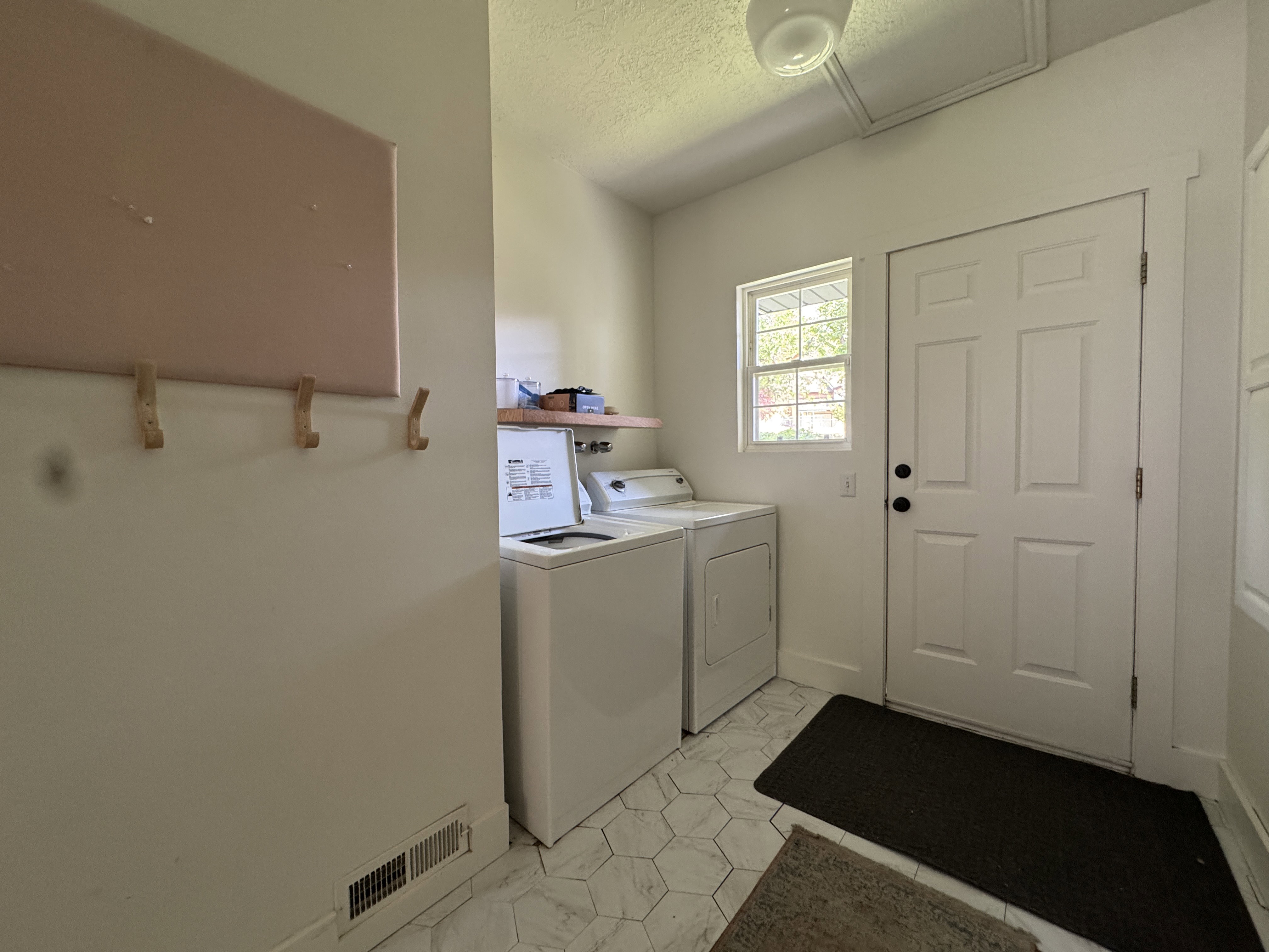 Laundry area featuring a window, paneled door with black hardware, and hexagonal floor tiling