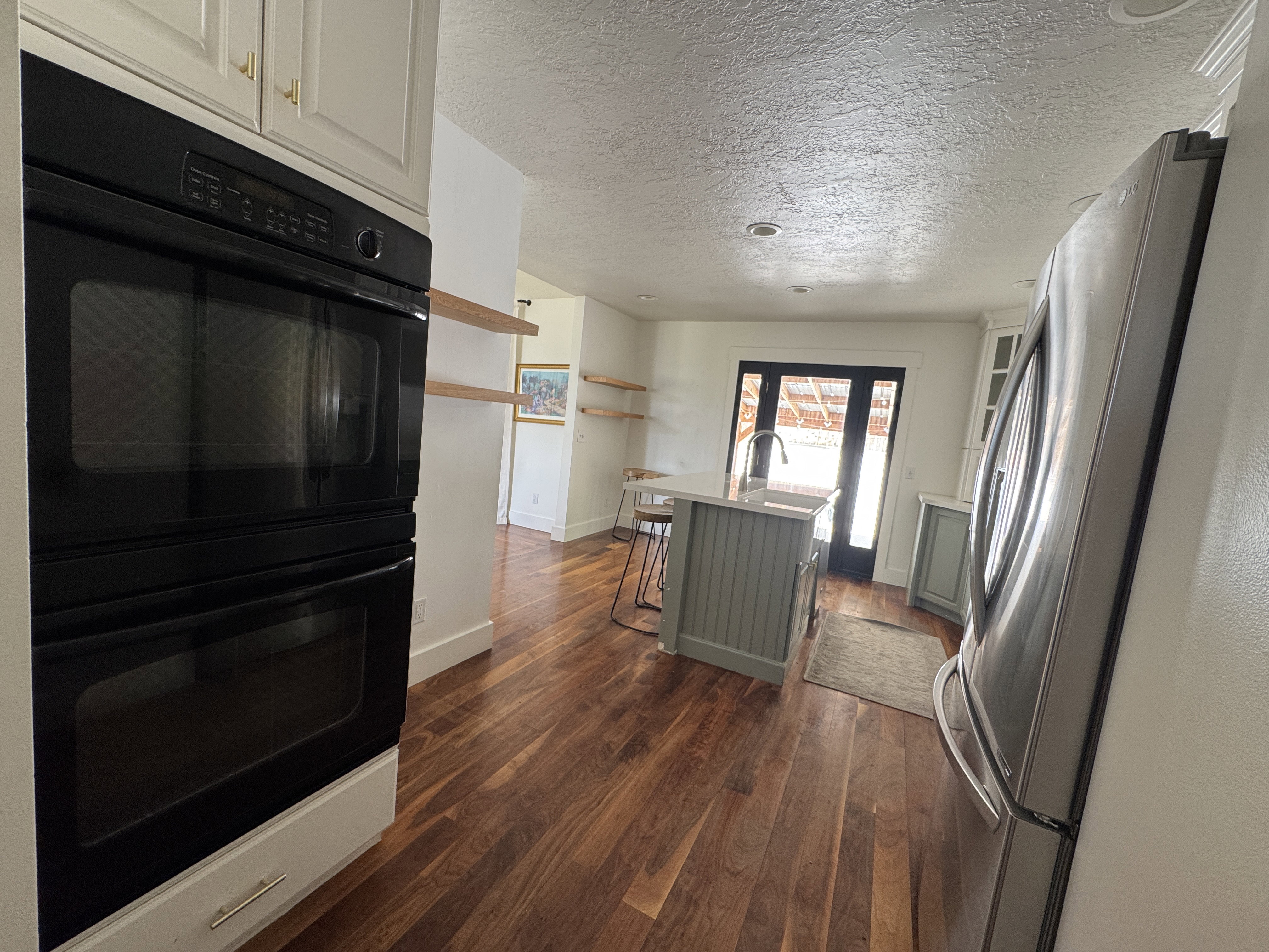 Gleaming wood-finish flooring complements the kitchen's built-in double ovens and stainless steel refrigerator