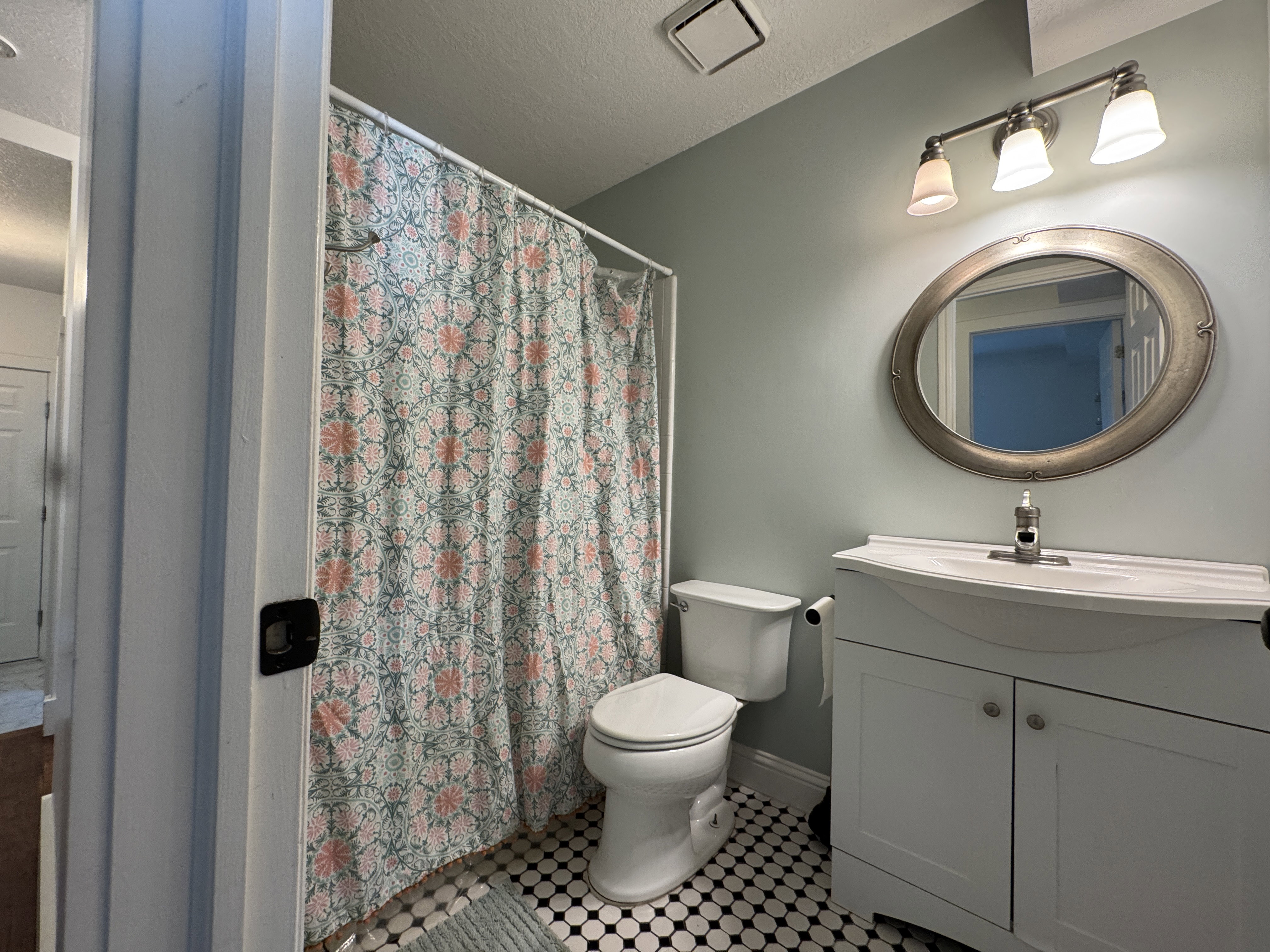 Bathroom featuring a white vanity with a single basin, an oval-framed mirror, and a three-light vanity fixture