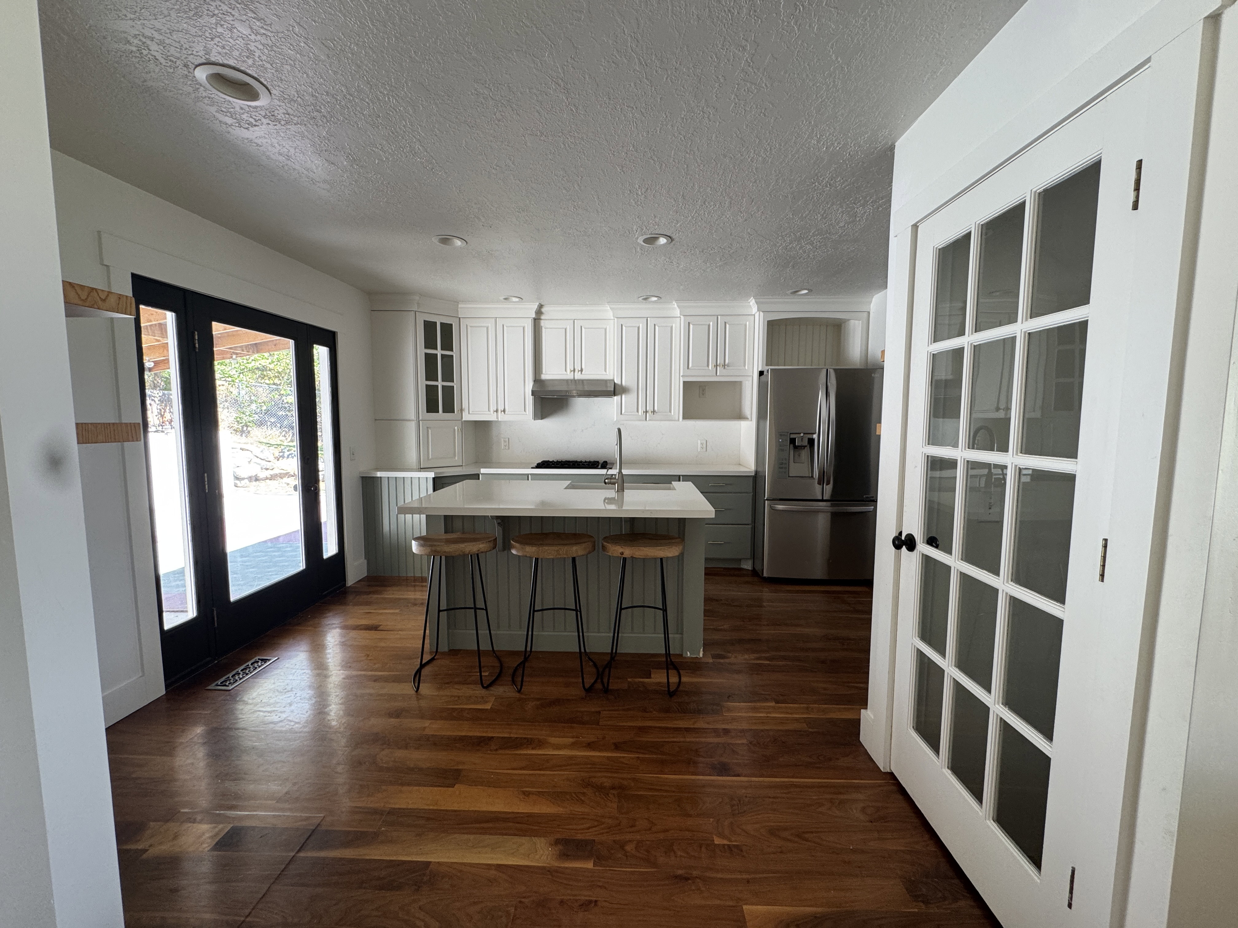 Kitchen with wood-finish flooring, two-tone cabinetry, and a central island with countertop seating