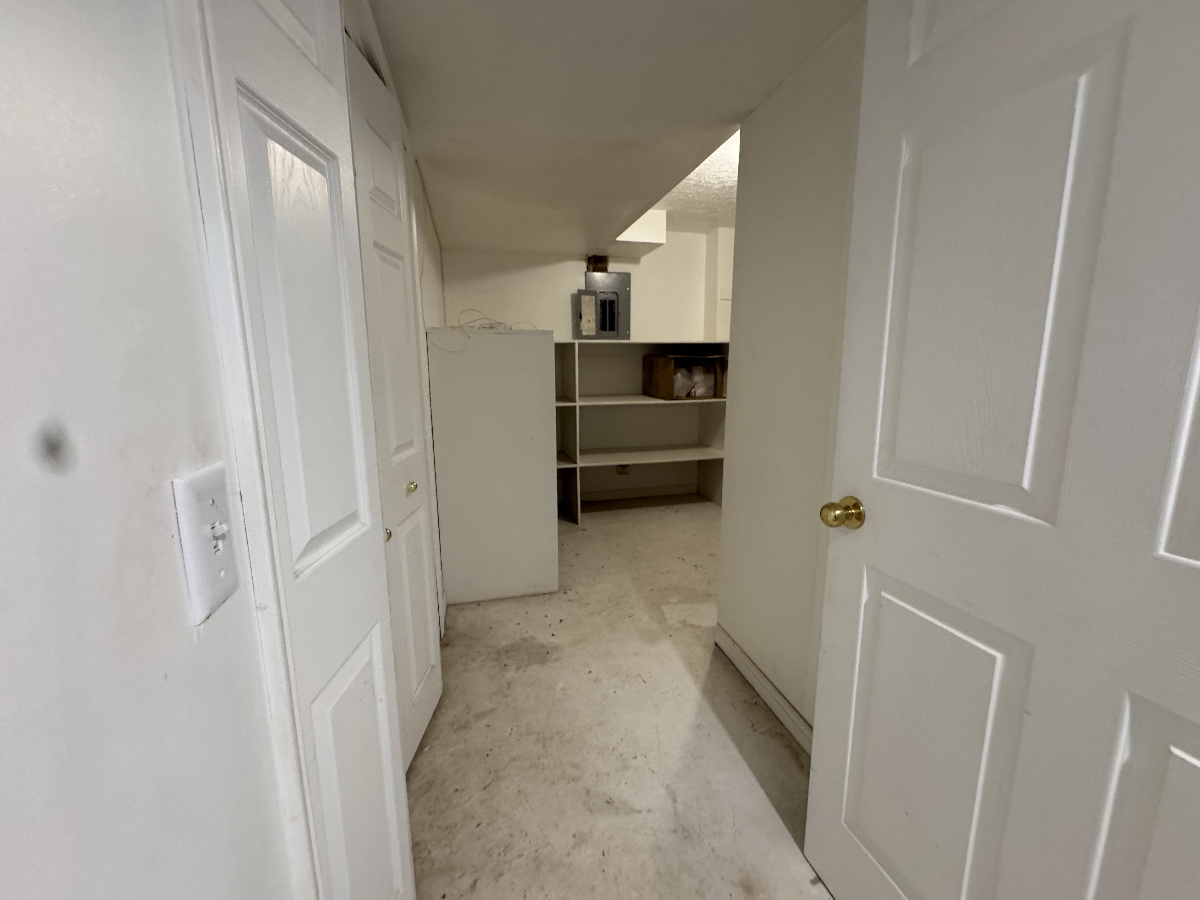 Utility area featuring light-toned flooring, white walls, and built-in shelving units