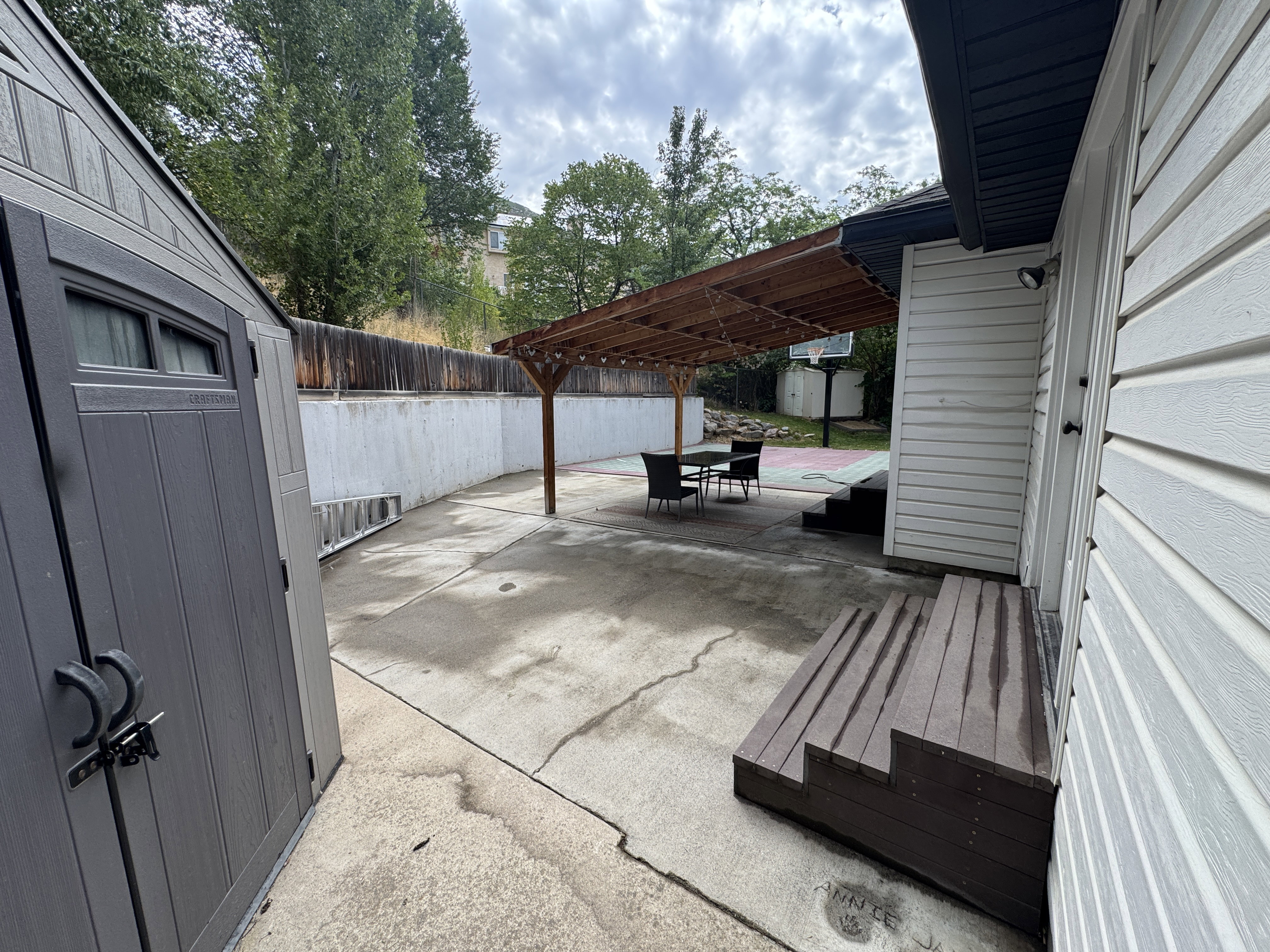 Rear patio area featuring a slatted wood pergola, concrete patio, a multi-level composite deck, and a detached storage shed