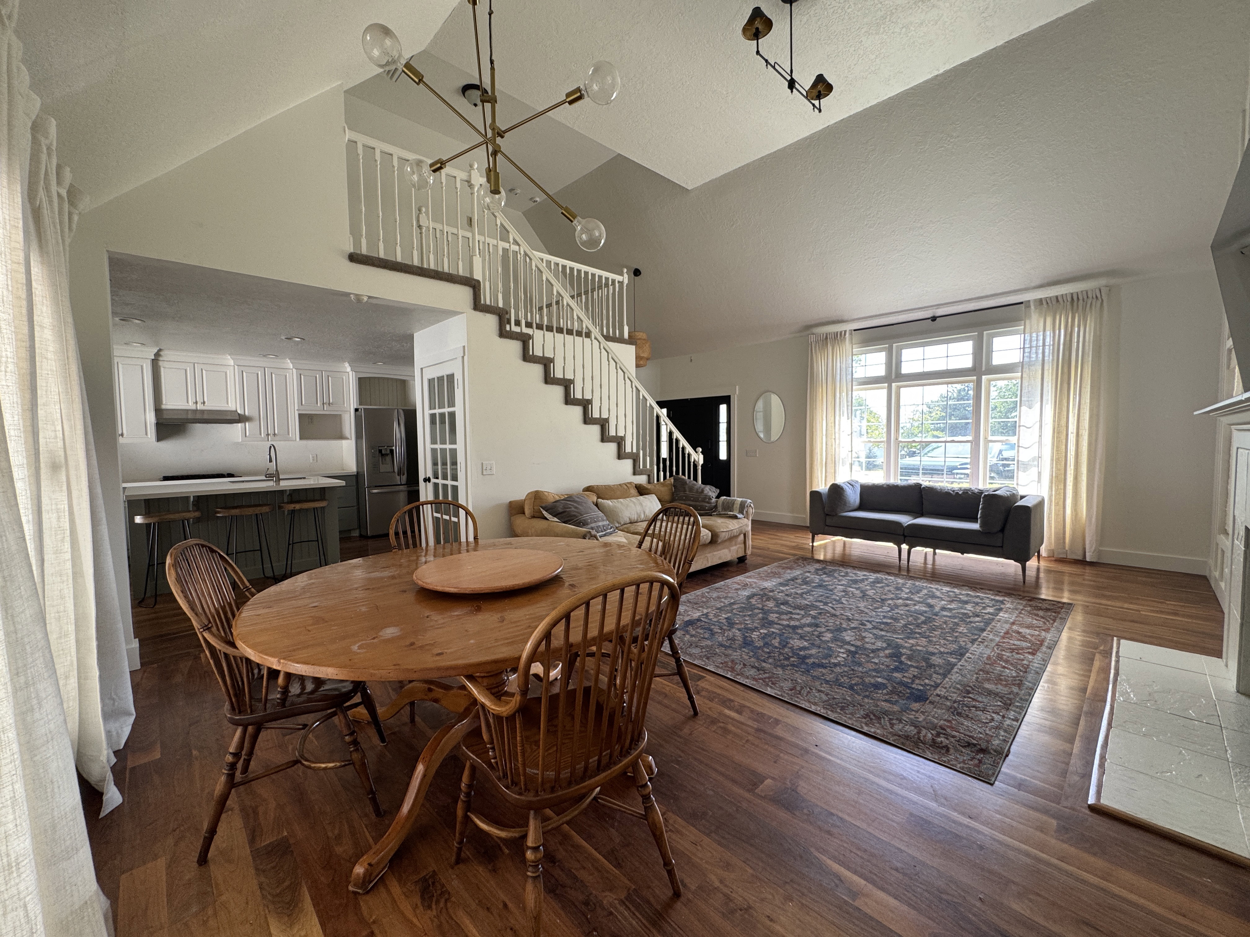 Dining area with wood-finish flooring, vaulted ceiling, and an open concept kitchen beyond