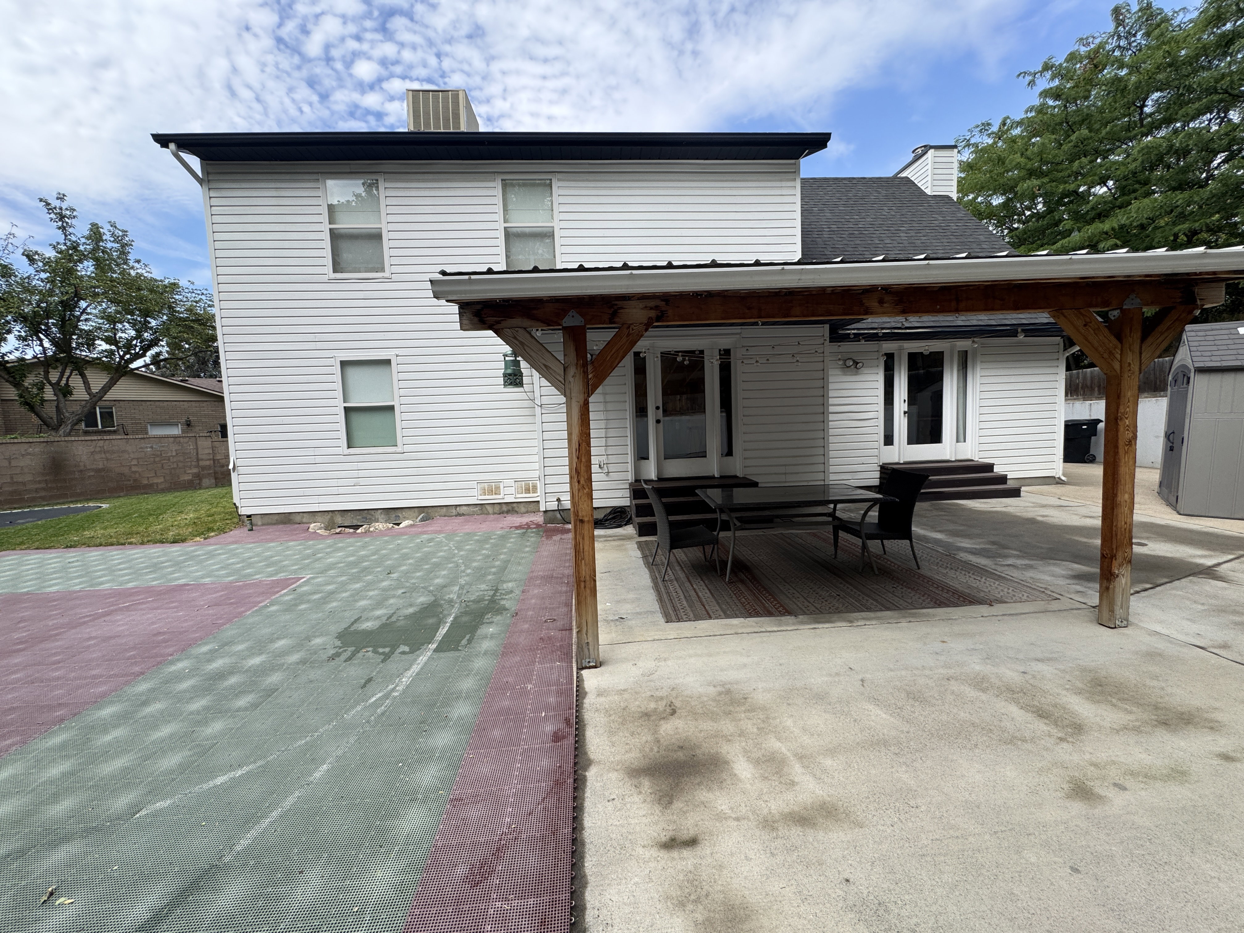 Backyard patio featuring a wood pergola, concrete surfaces, and a two-story exterior with white siding