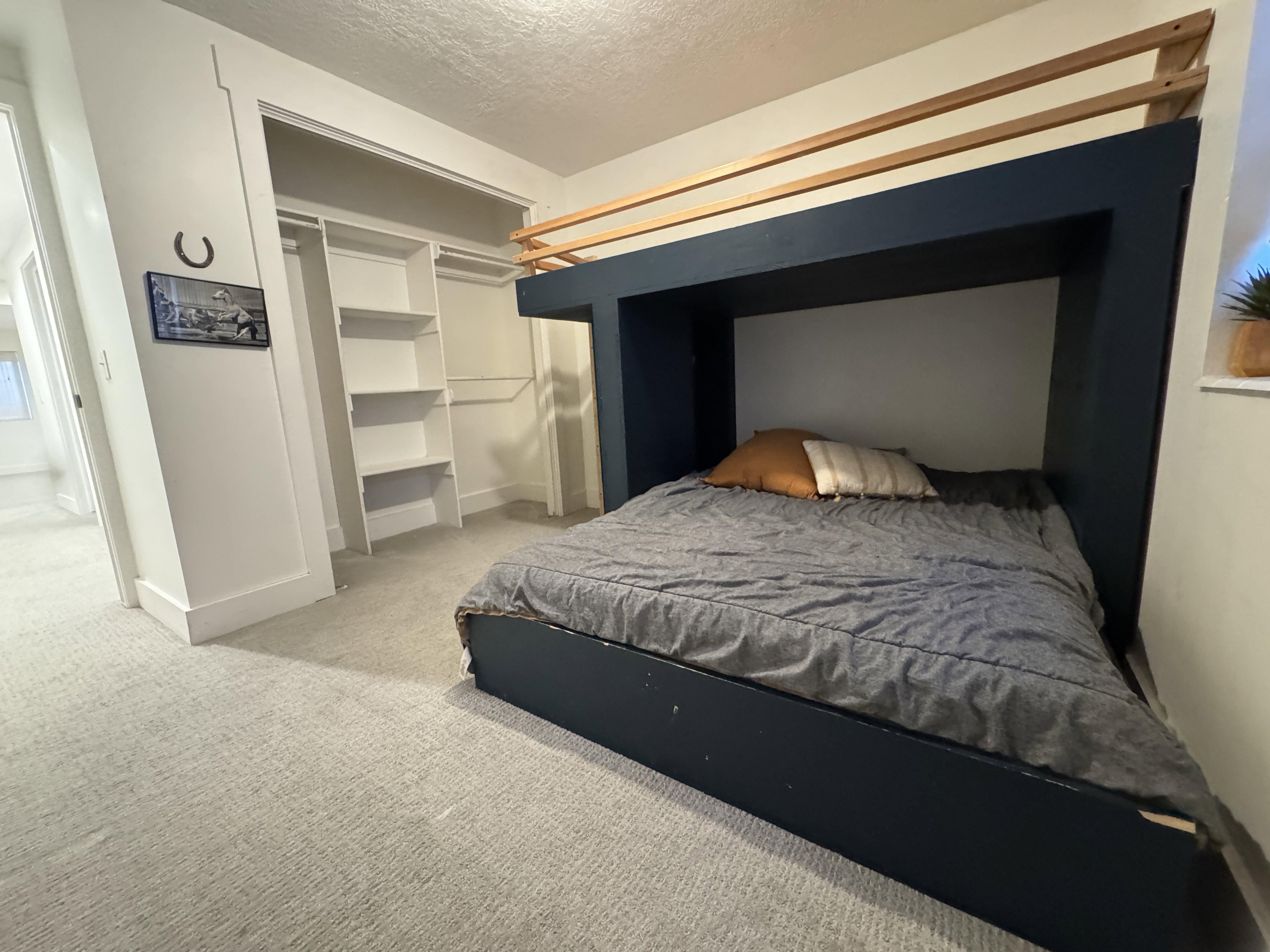 Built-in bed frame with a contrasting wood-tone headboard element, paired with light-toned carpeting