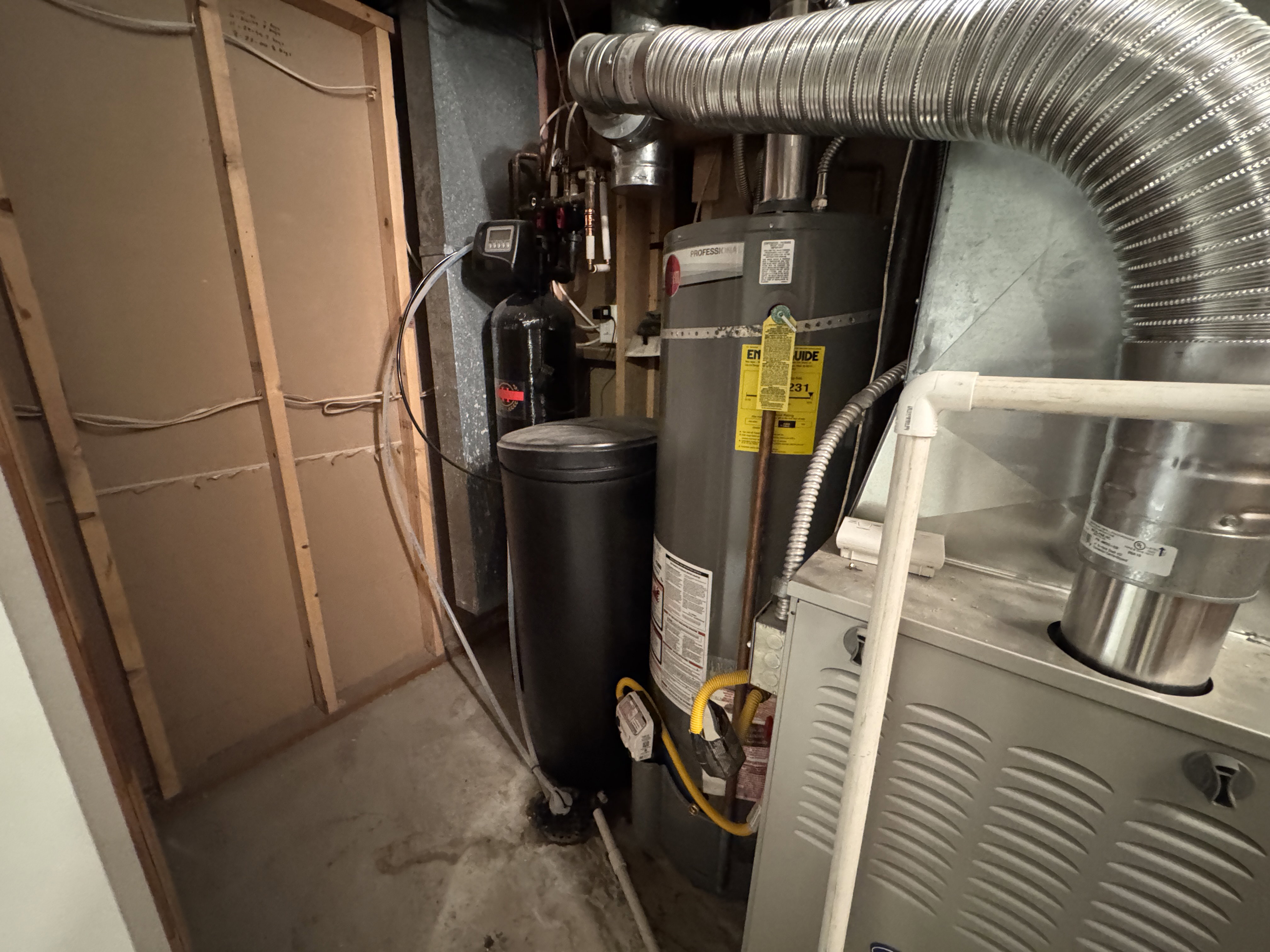 Mechanical room featuring a water heater, water softener, and furnace with aluminum ductwork