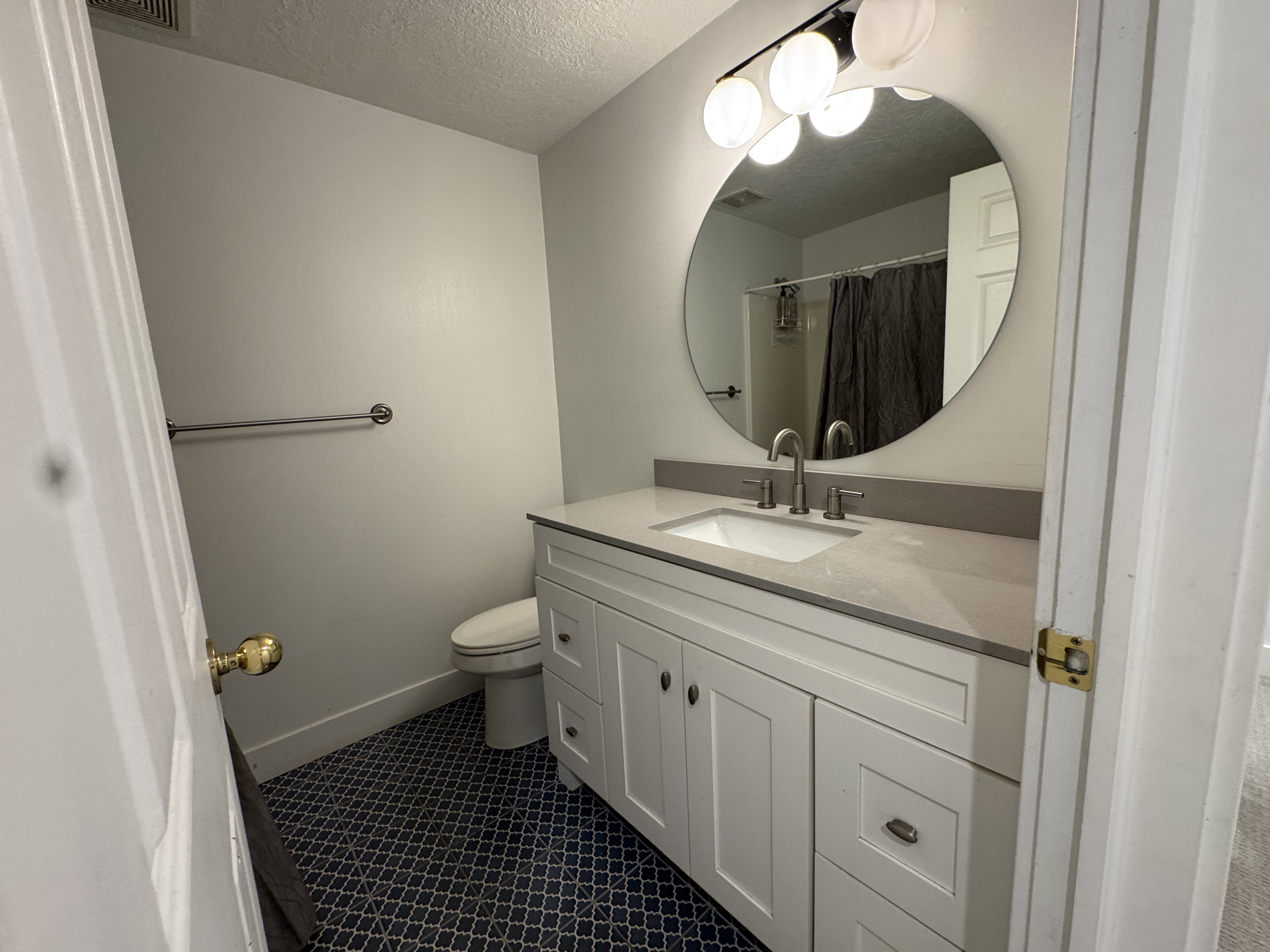 Contemporary bathroom featuring a white vanity with shaker-style cabinetry, an integrated sink, and a light-toned countertop