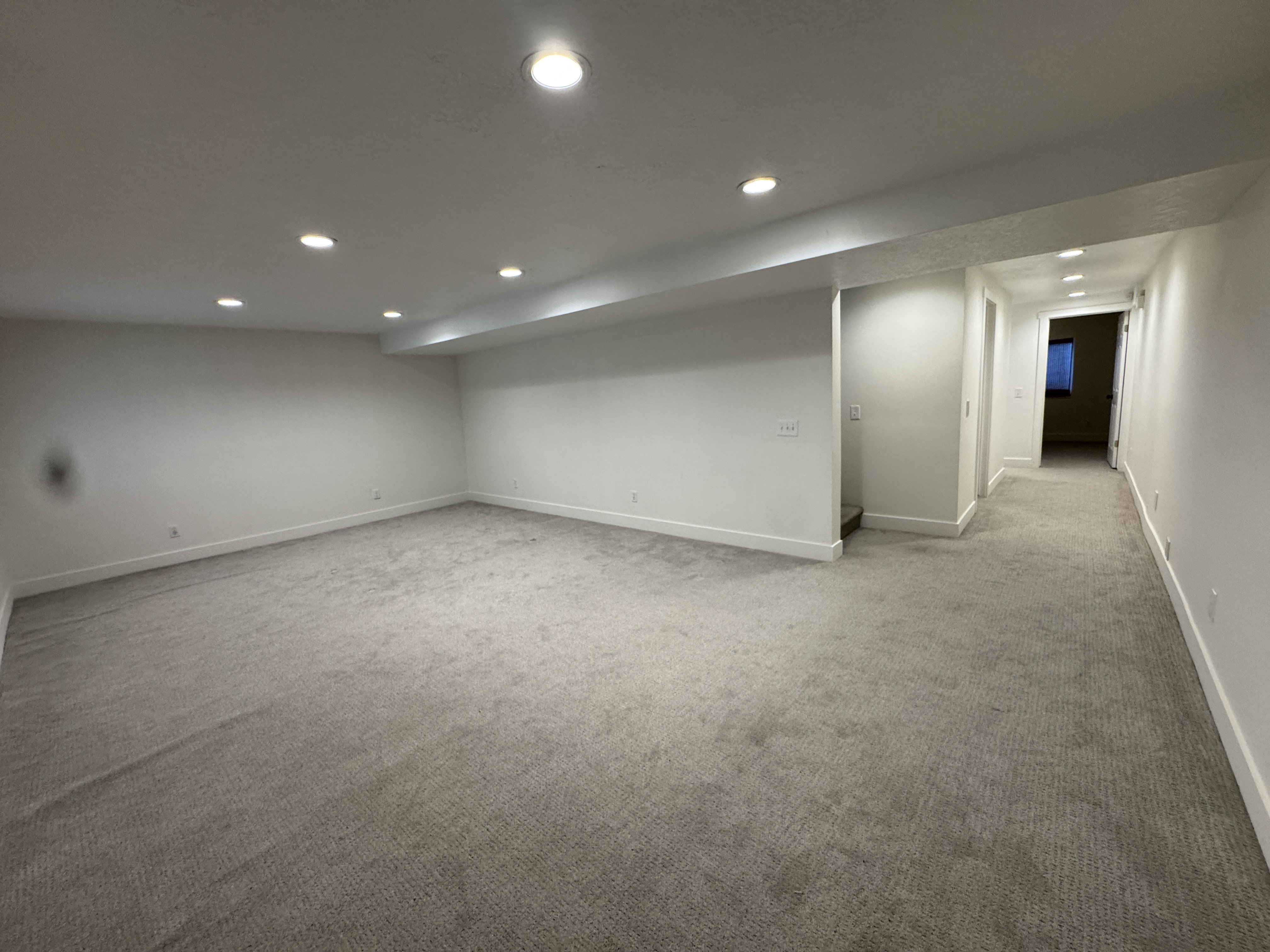 Spacious room with new neutral carpeting, recessed ceiling lighting, crisp white walls, and bright white baseboards