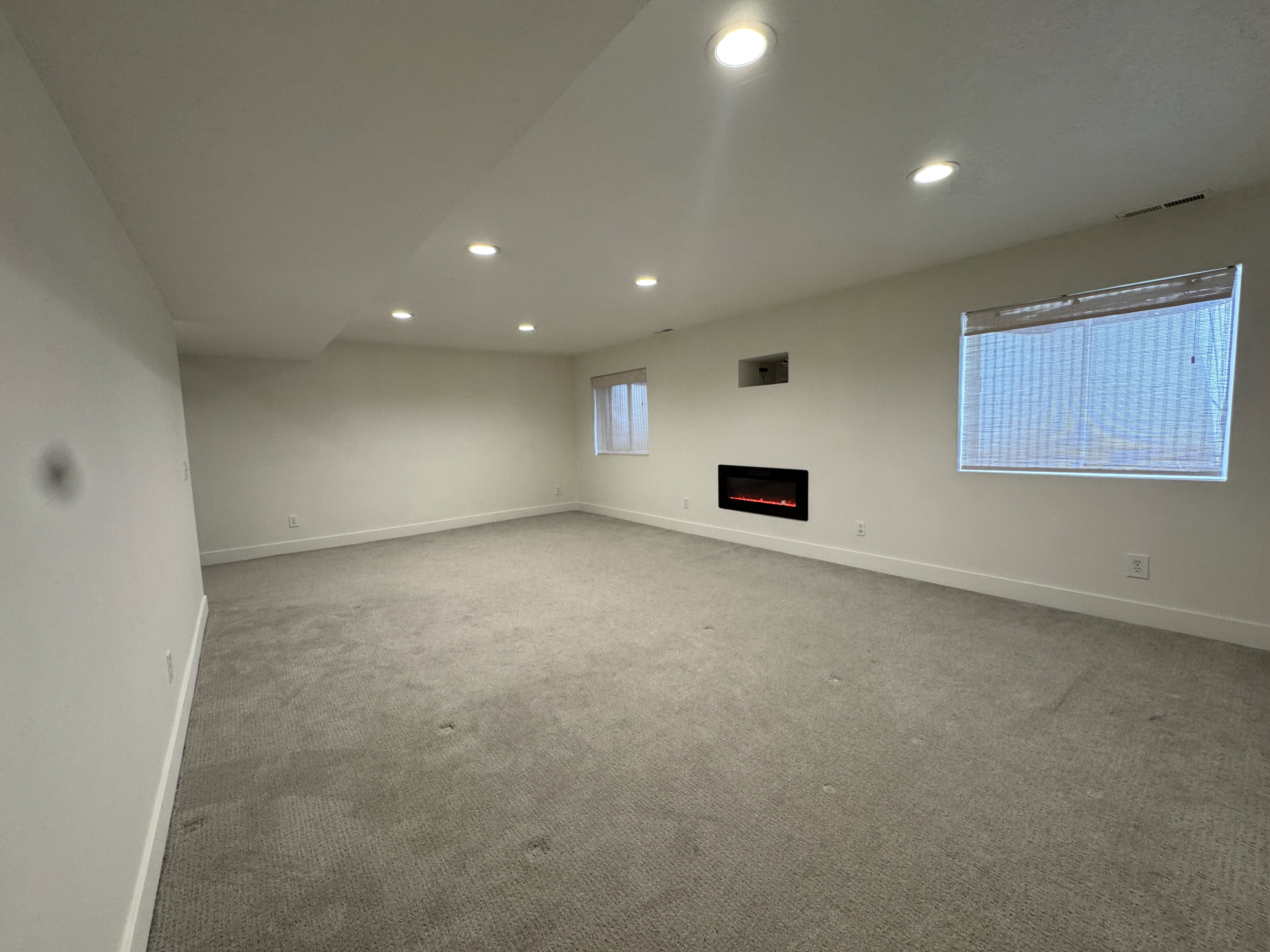 Spacious room featuring light gray carpeting and white walls