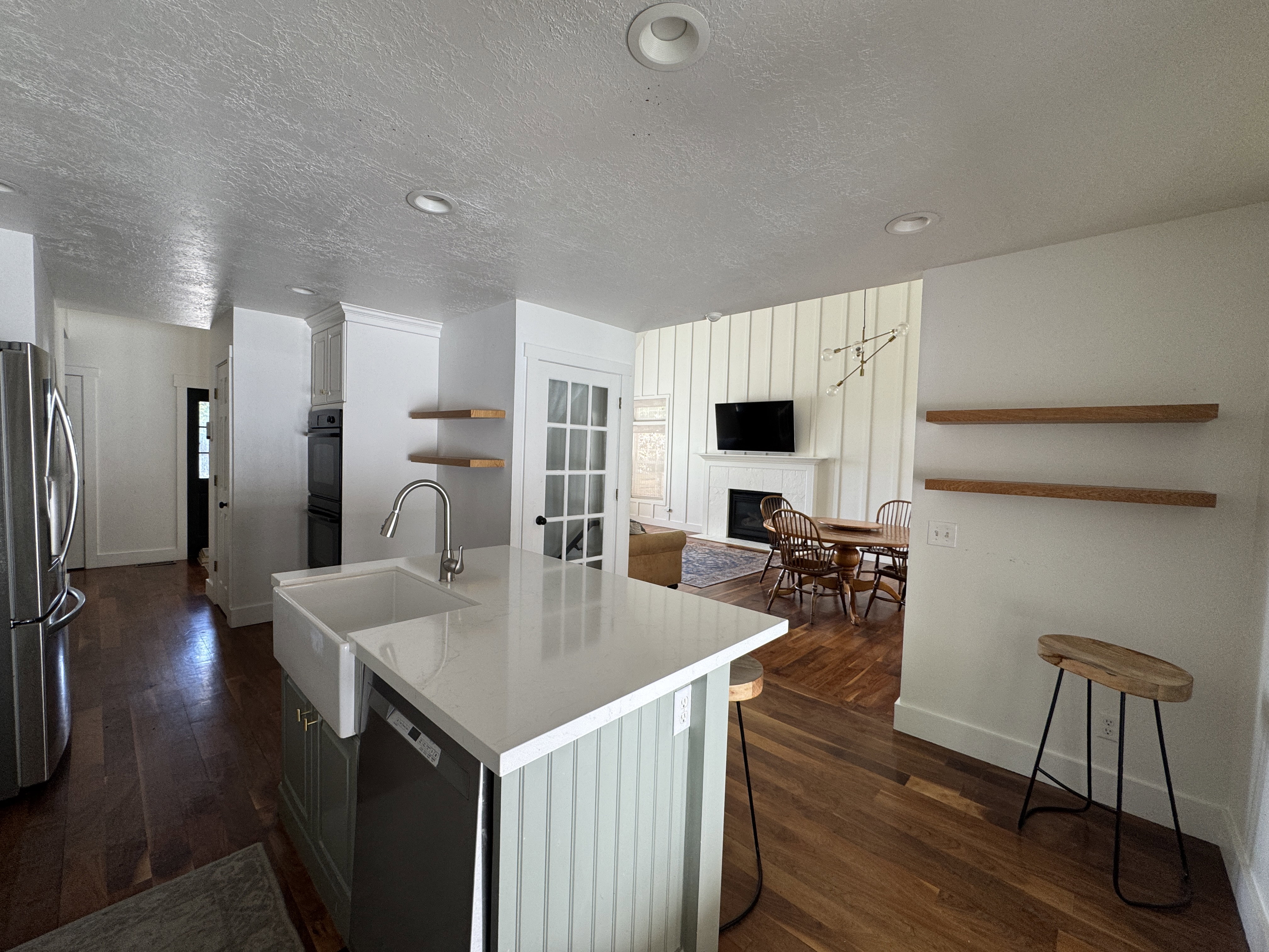Kitchen island with white farmhouse sink, stainless steel faucet, and dishwasher