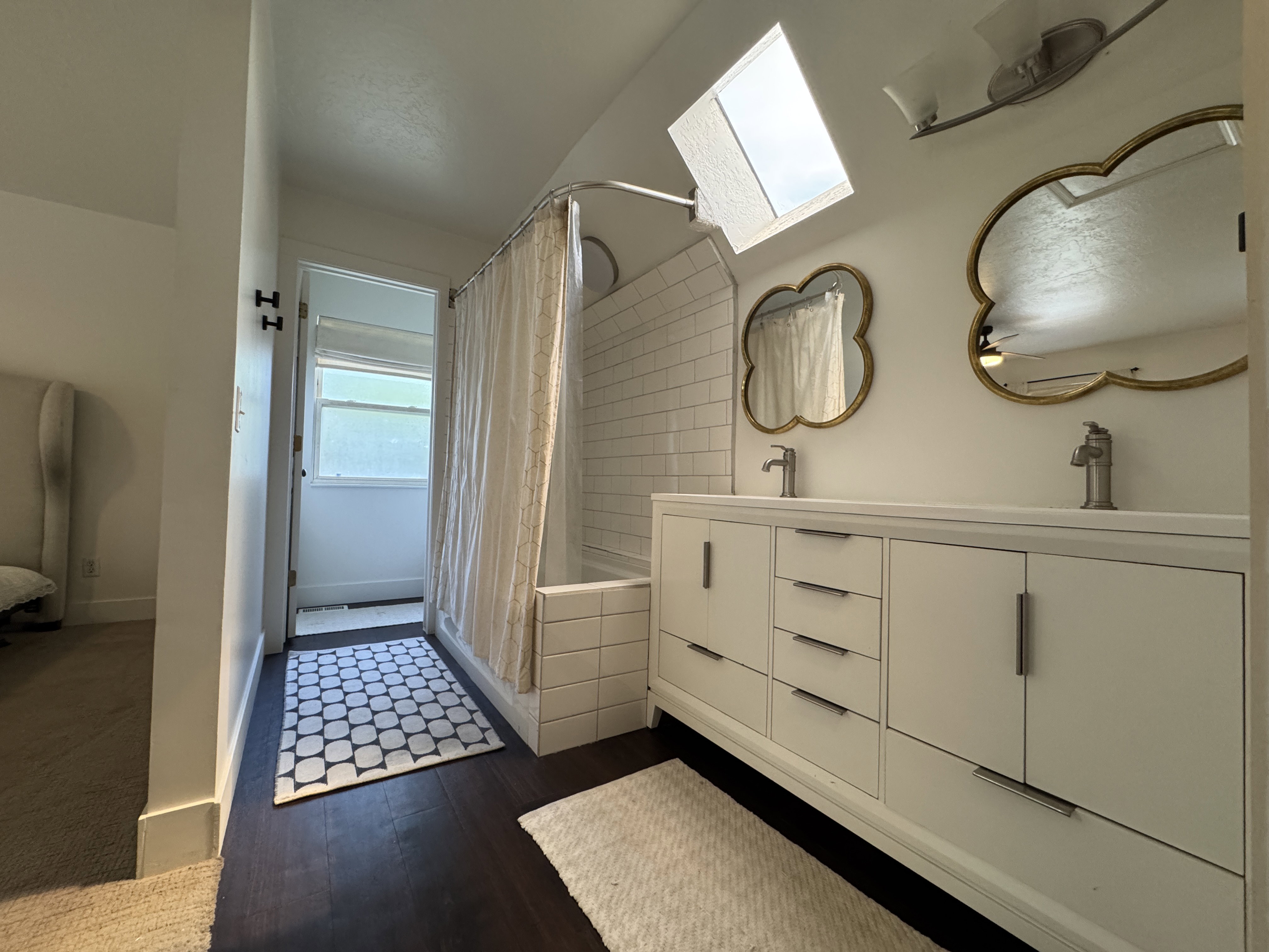 Bright bathroom featuring a dual vanity with white cabinetry and brushed nickel hardware