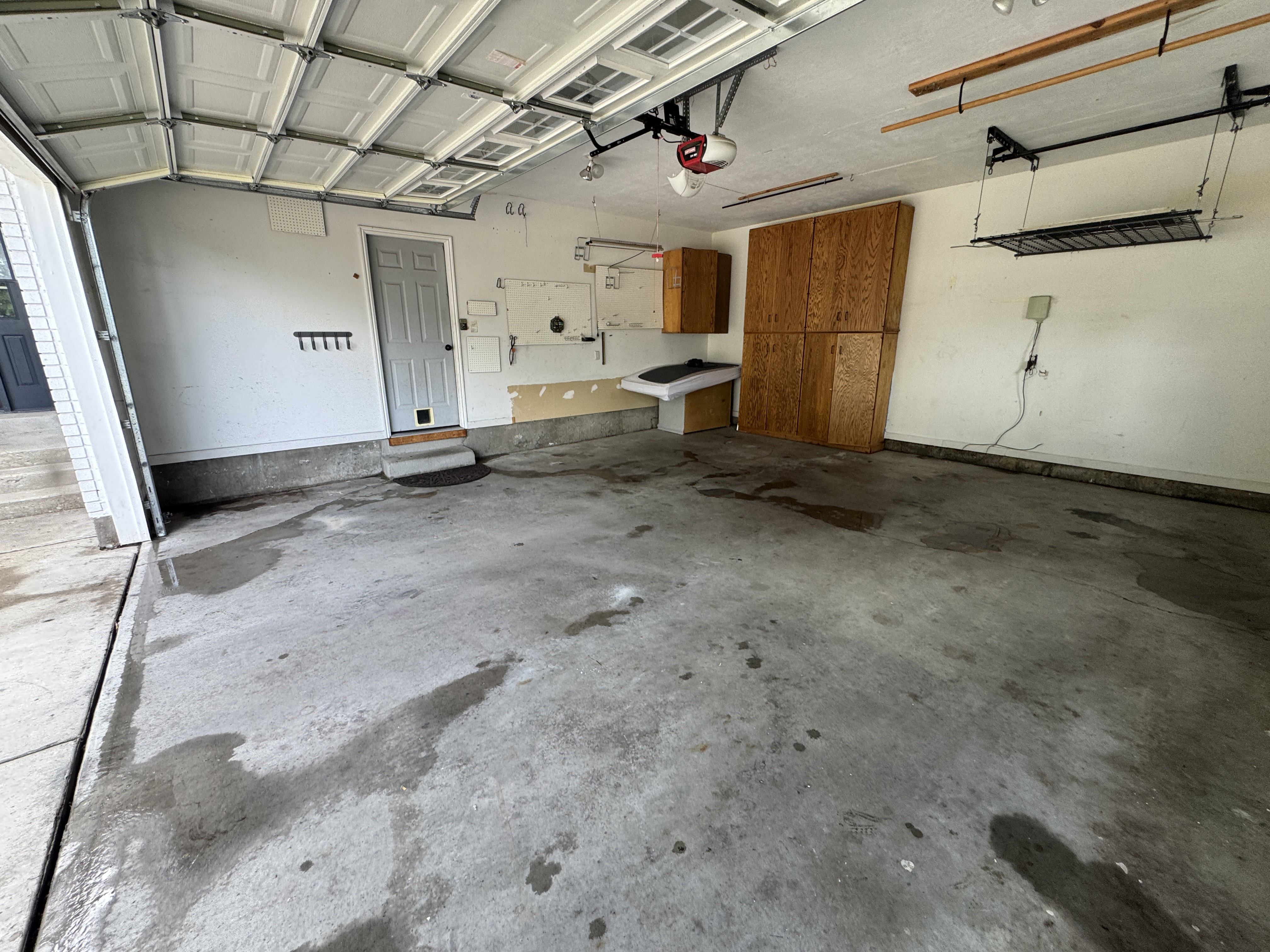 Spacious garage featuring a concrete floor, built-in wooden cabinetry, and overhead shelving for storage