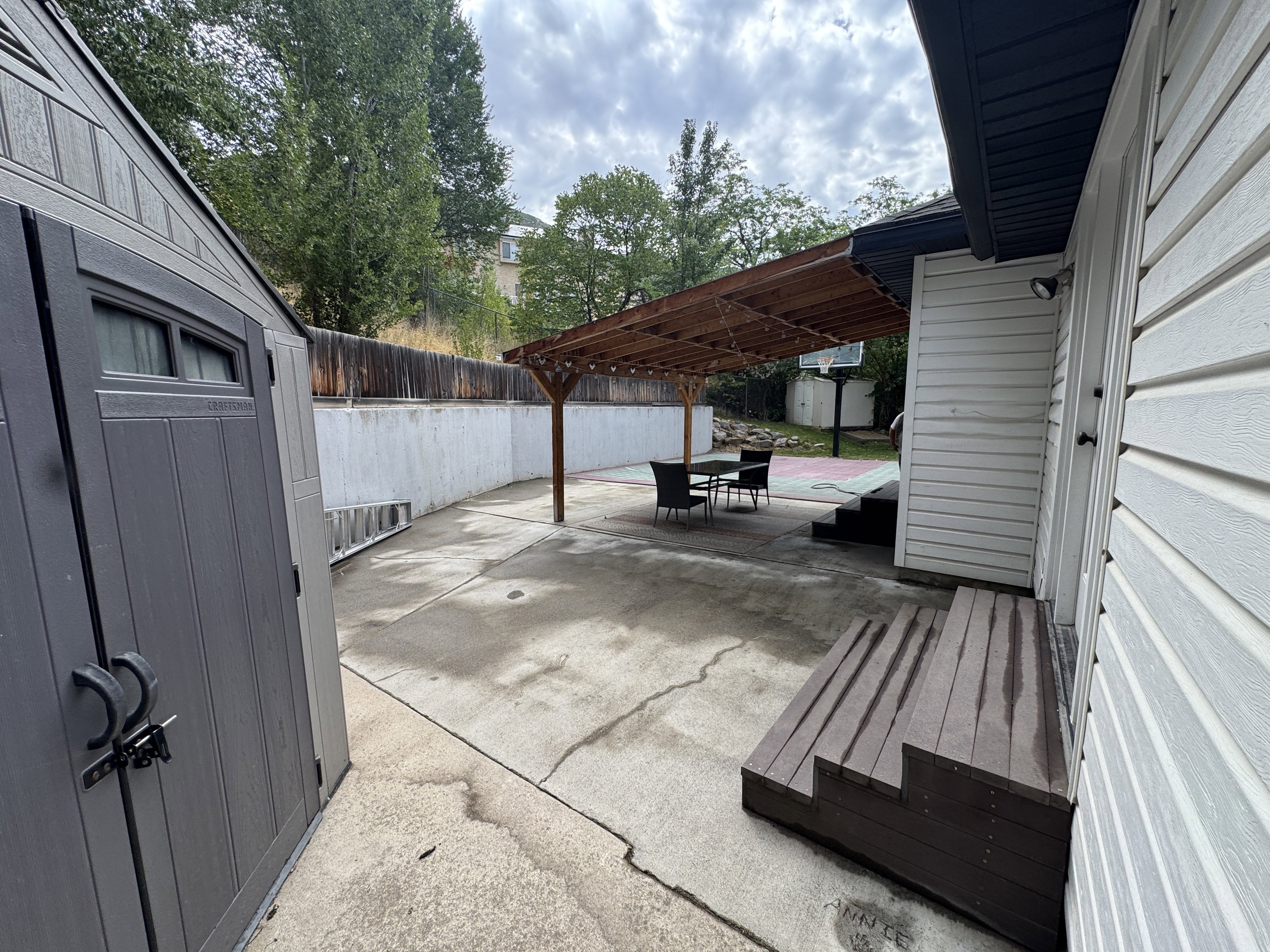 Expansive concrete patio featuring a wood pergola and privacy fence
