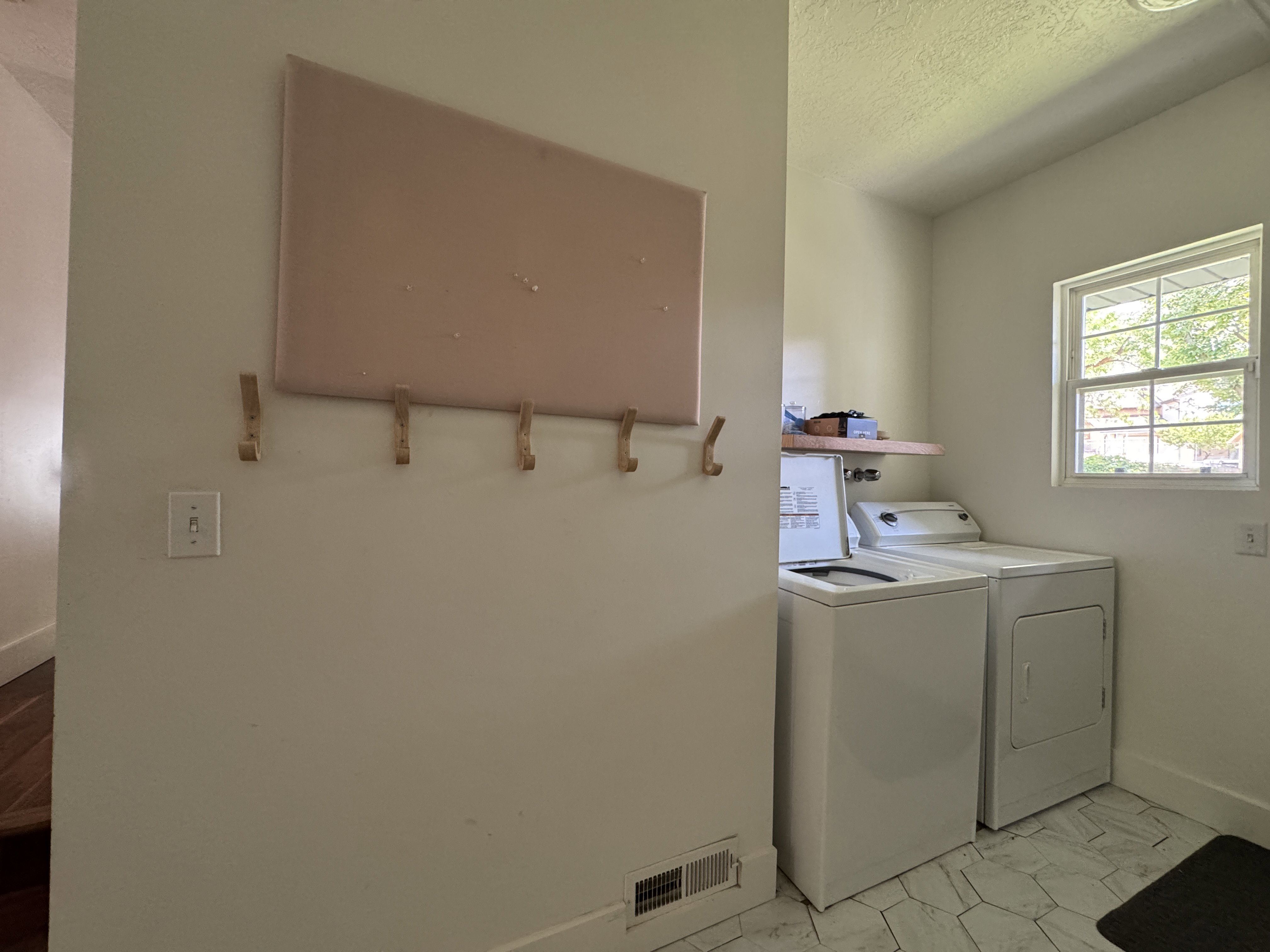 Laundry area featuring a window, tile flooring, and a wall-mounted wooden shelf