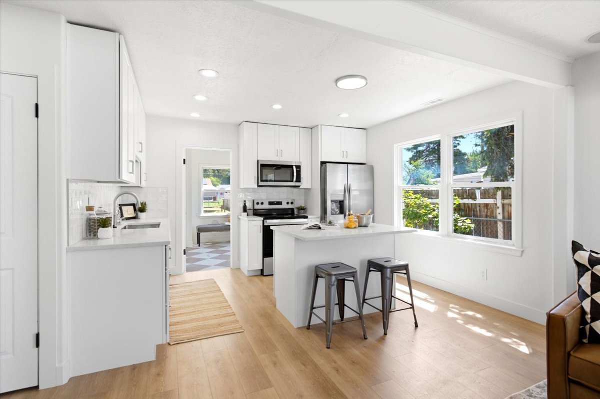 Bright kitchen featuring white cabinetry, light-toned wood-finish flooring, and a central island with a light-colored countertop