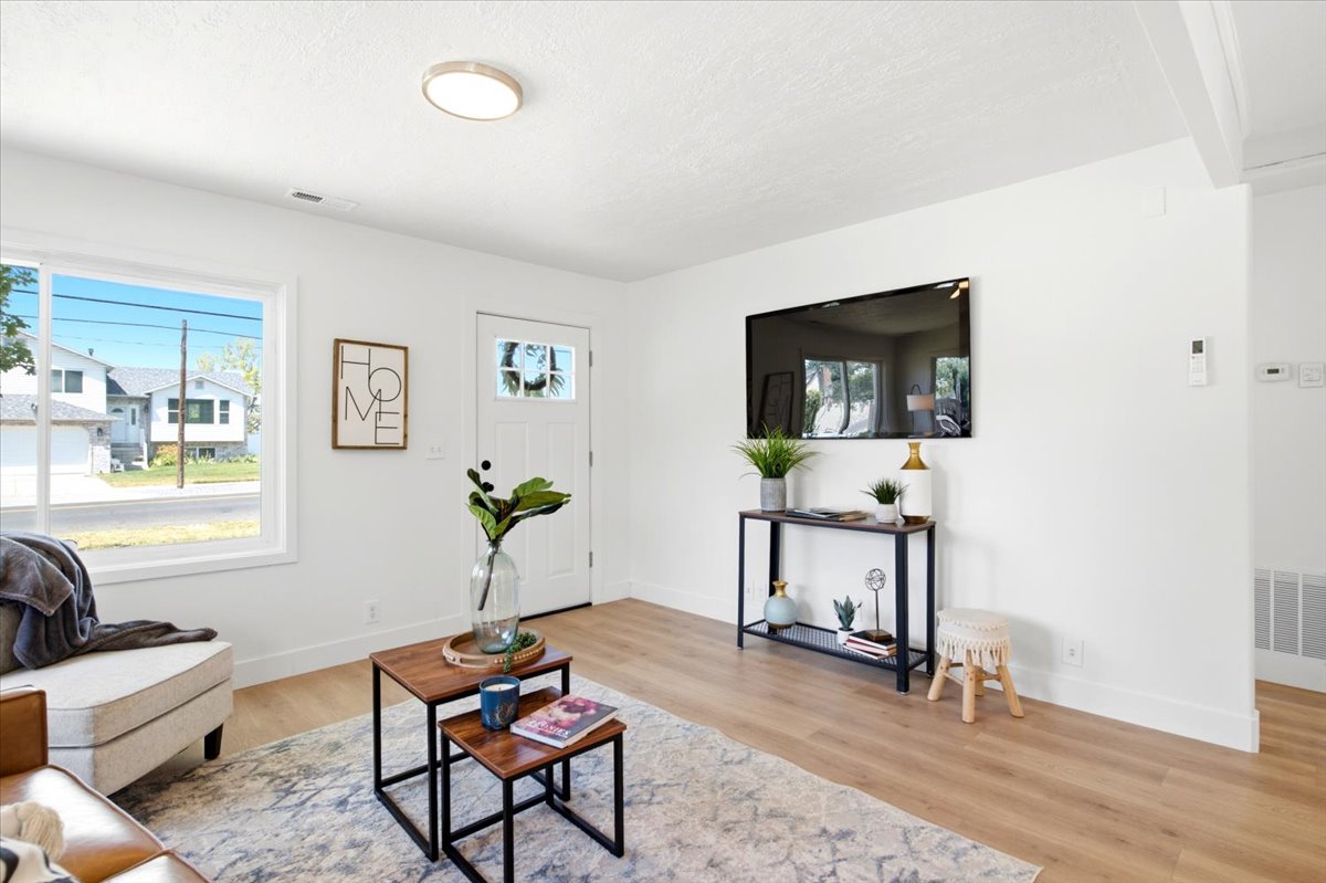 Bright living area featuring wood-finish flooring, white walls, and a large picture window