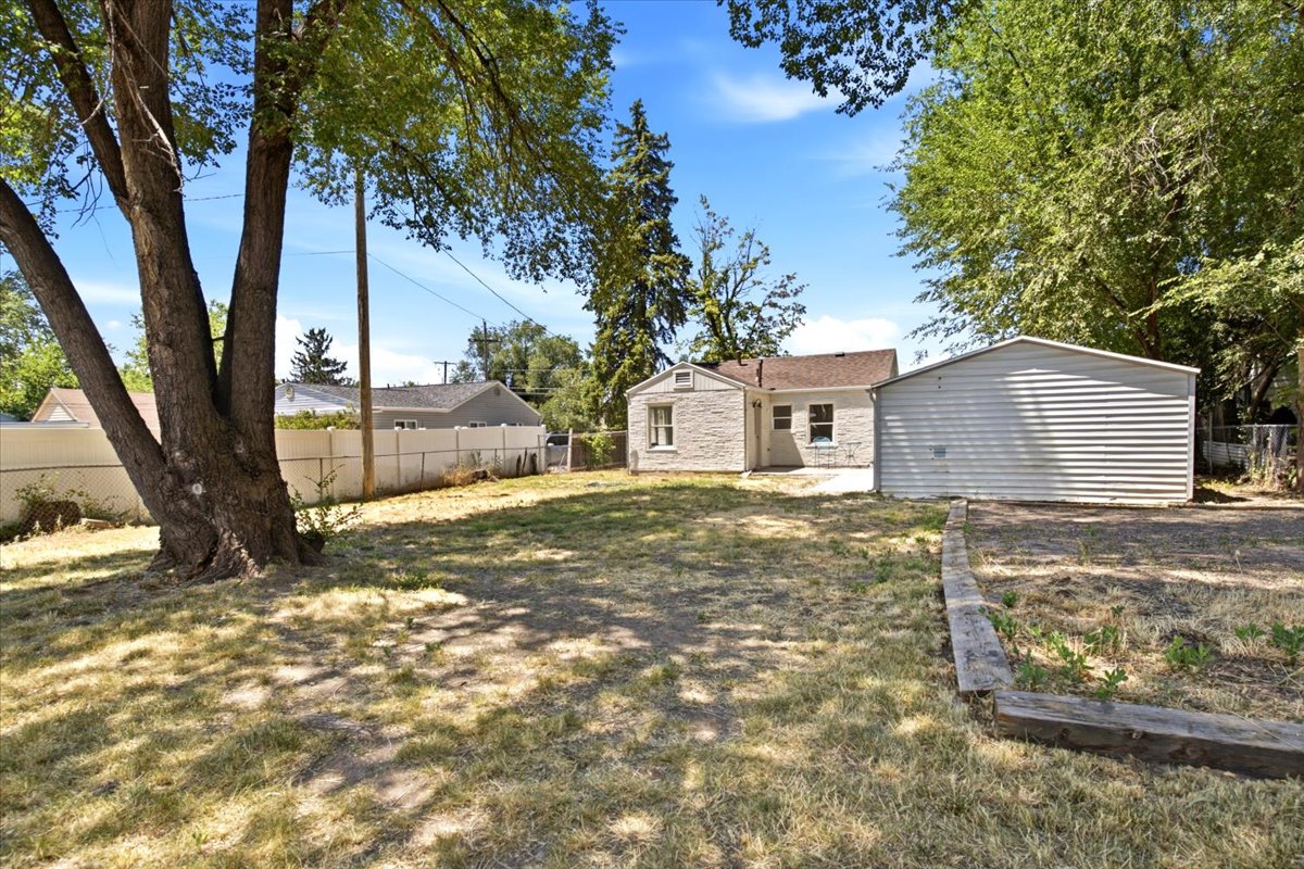 Expansive backyard featuring mature trees, a detached garage, and a privacy fence