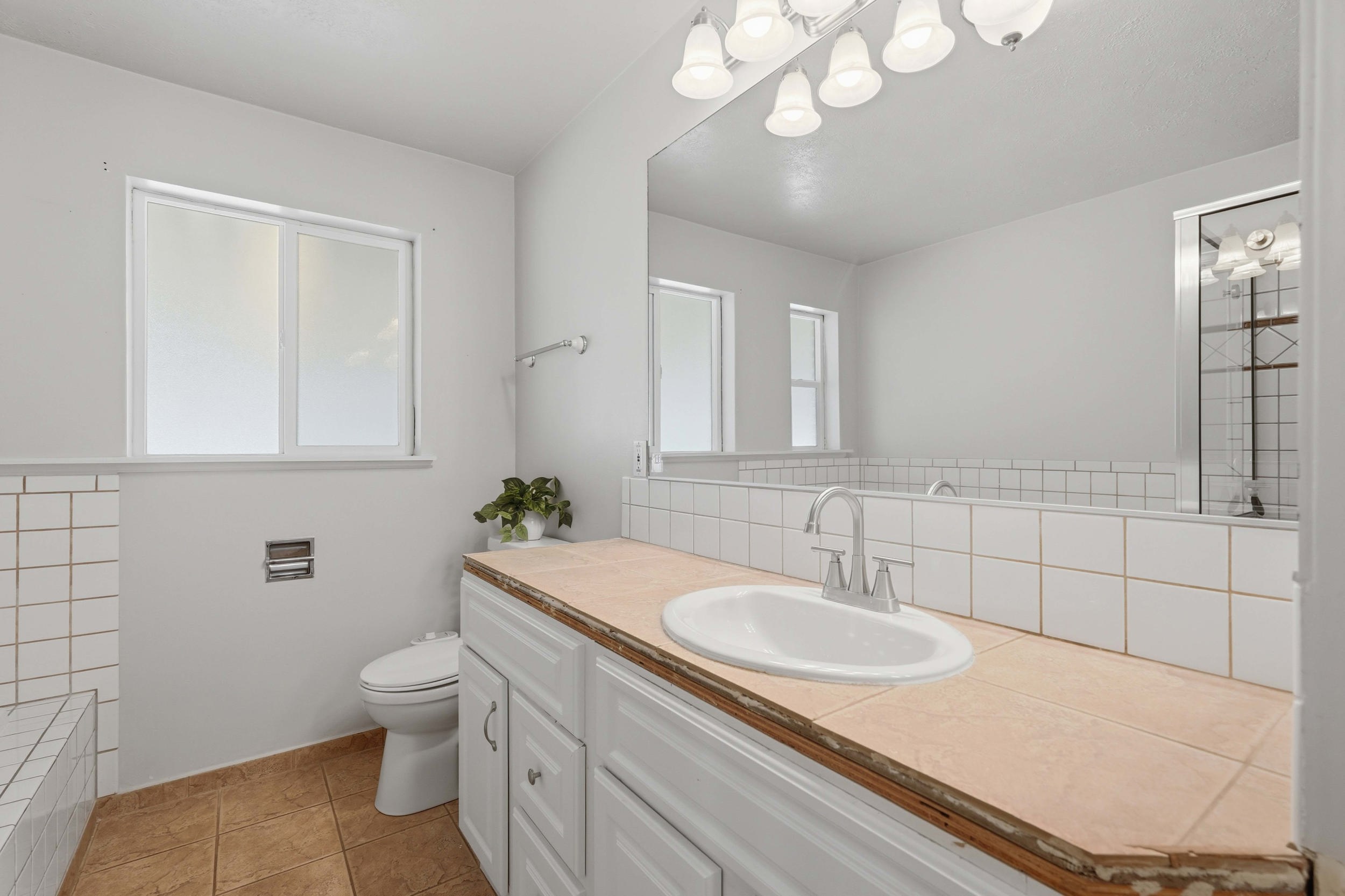 Bathroom vanity featuring a drop-in sink, dual-handle faucet, and white cabinetry
