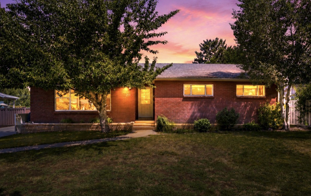 Brick exterior residence with mature trees and a front lawn