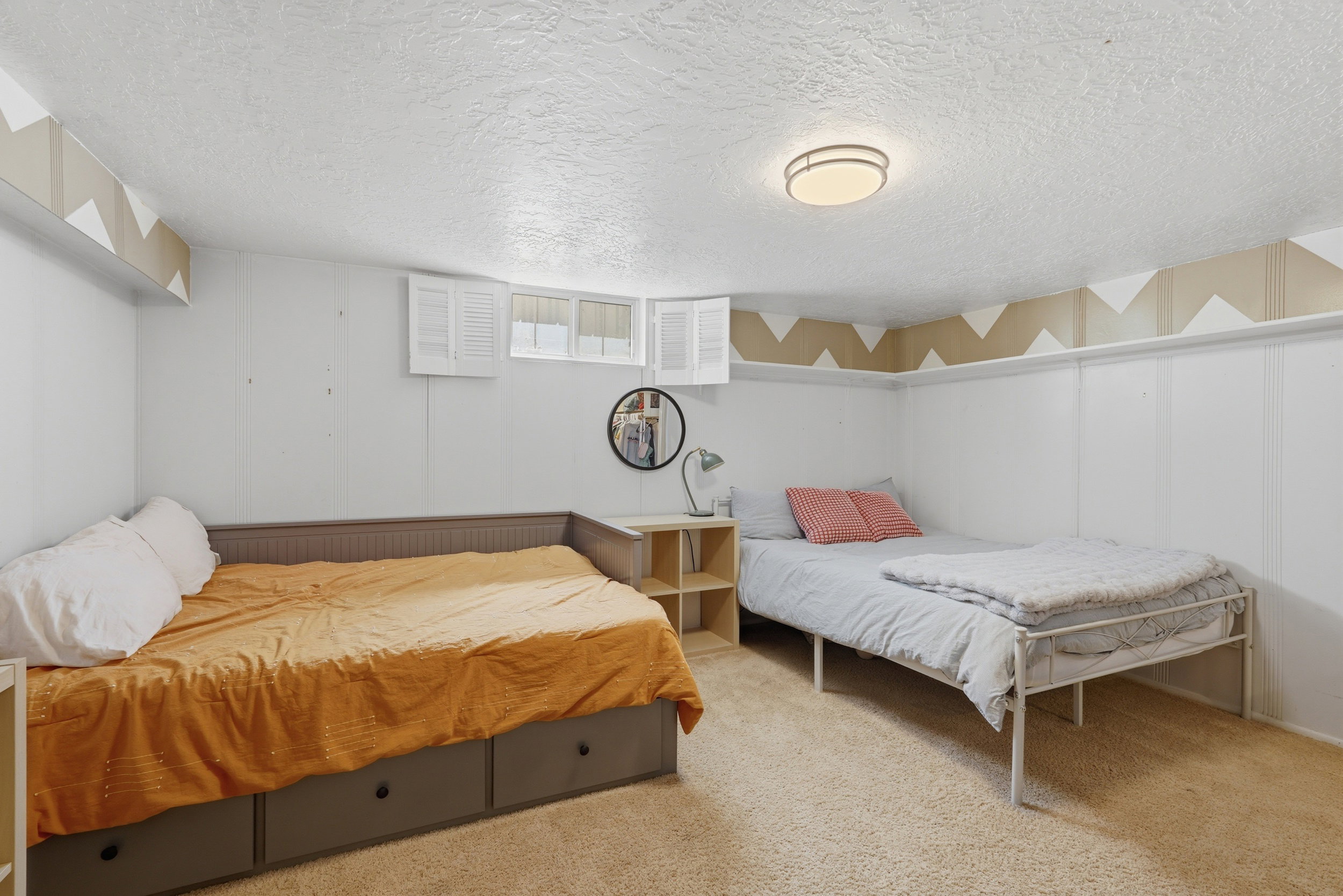 Carpeted room featuring white walls, a textured ceiling, a flush-mount ceiling light, and white window shutters